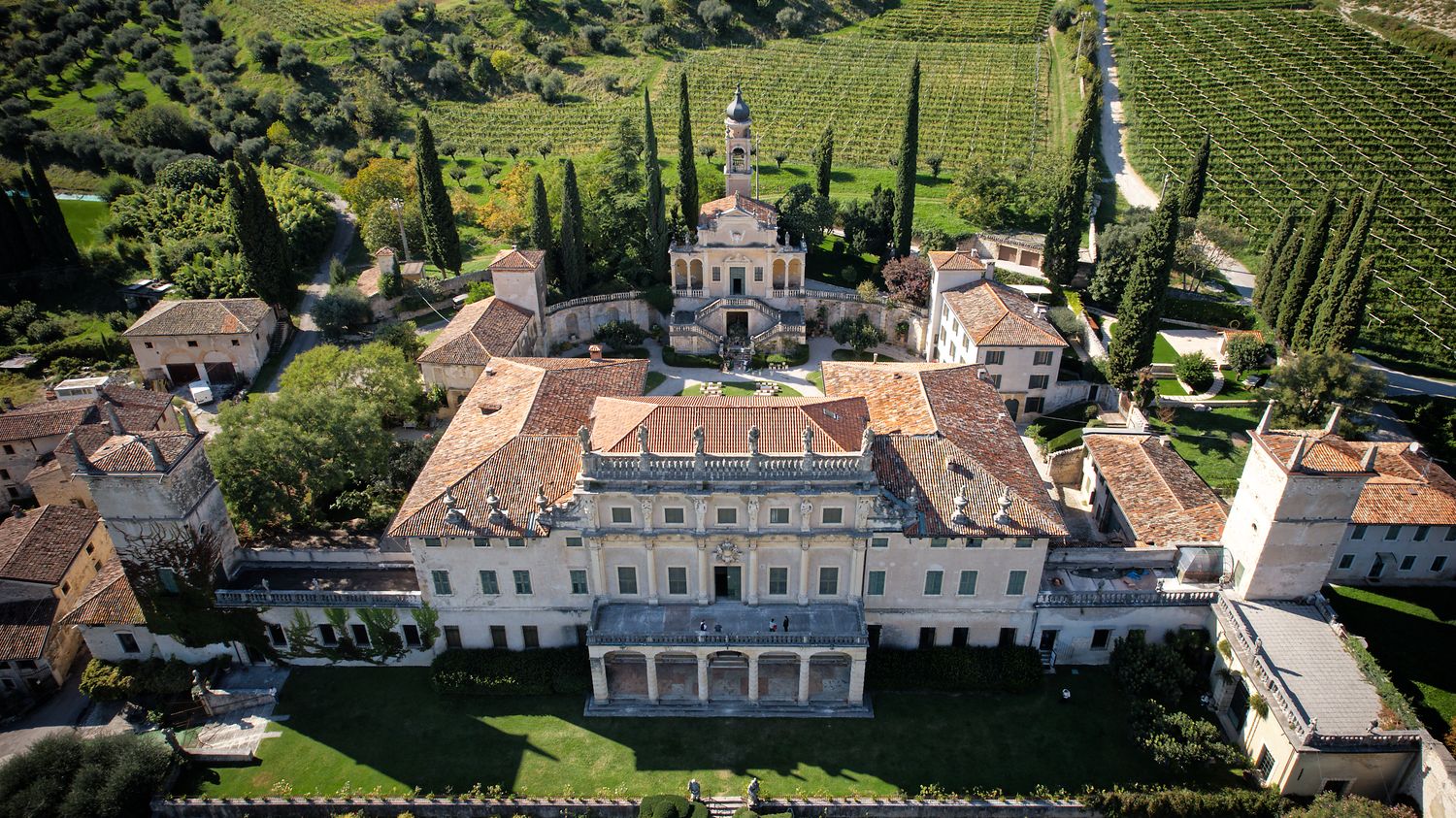 Aerial view of Villa Sandi winery estate with historic Italian architecture surrounded by lush vineyards in Veneto region.
