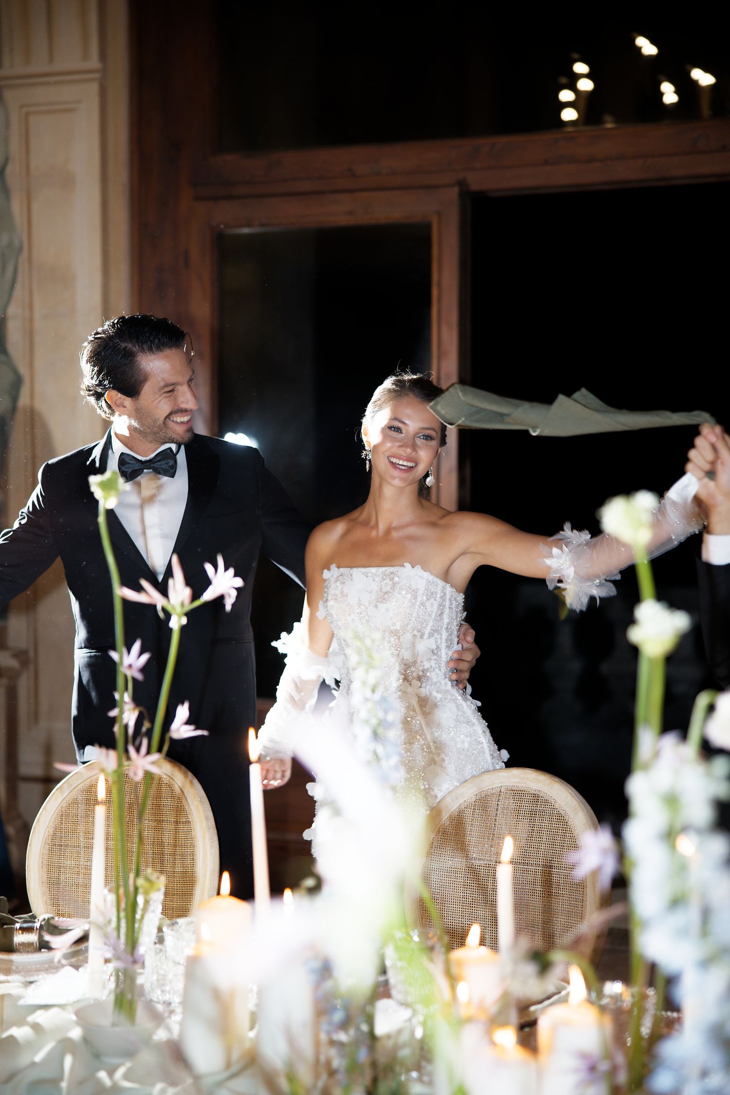 Joyful couple celebrates during wedding reception at ornate indoor venue.