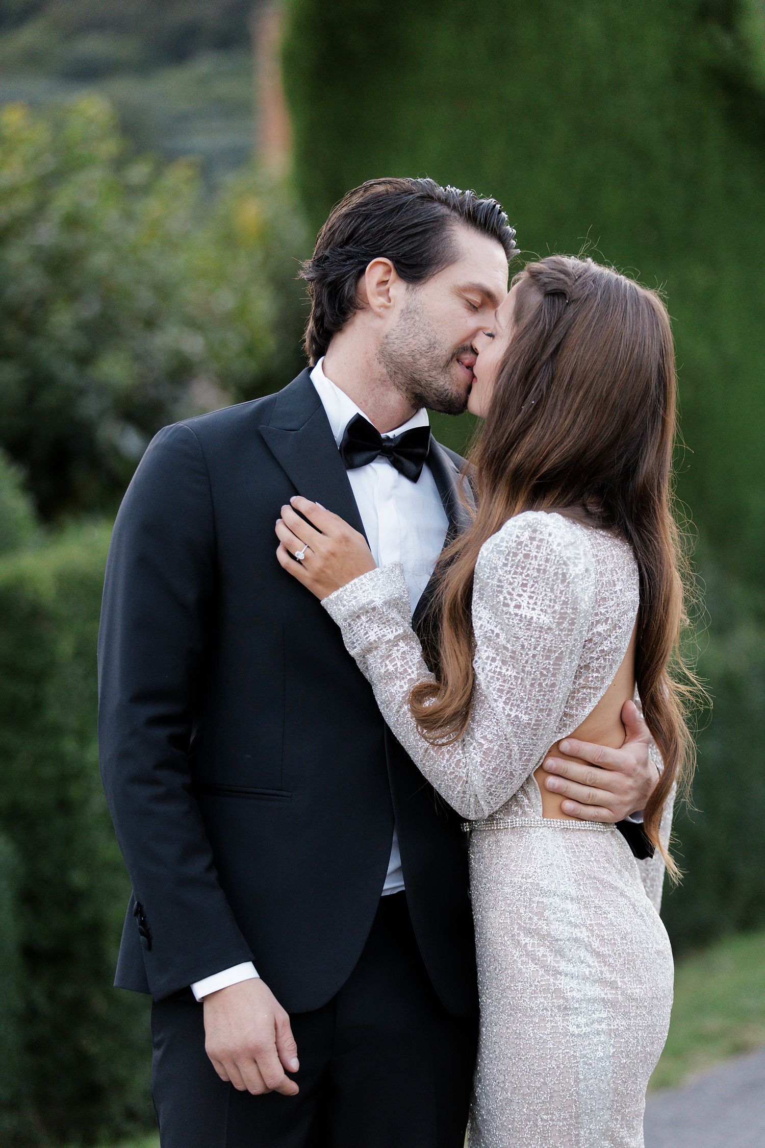 Romantic moment between couple in formal wear against garden backdrop.