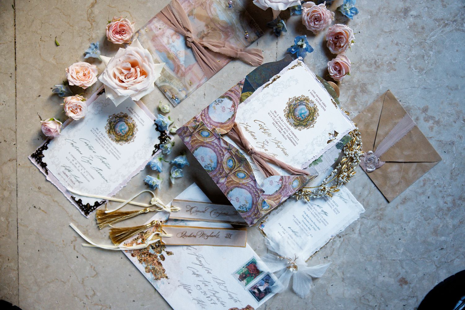 Wedding invitations and decor featuring pink roses, gold tassels, and elegant calligraphy.
