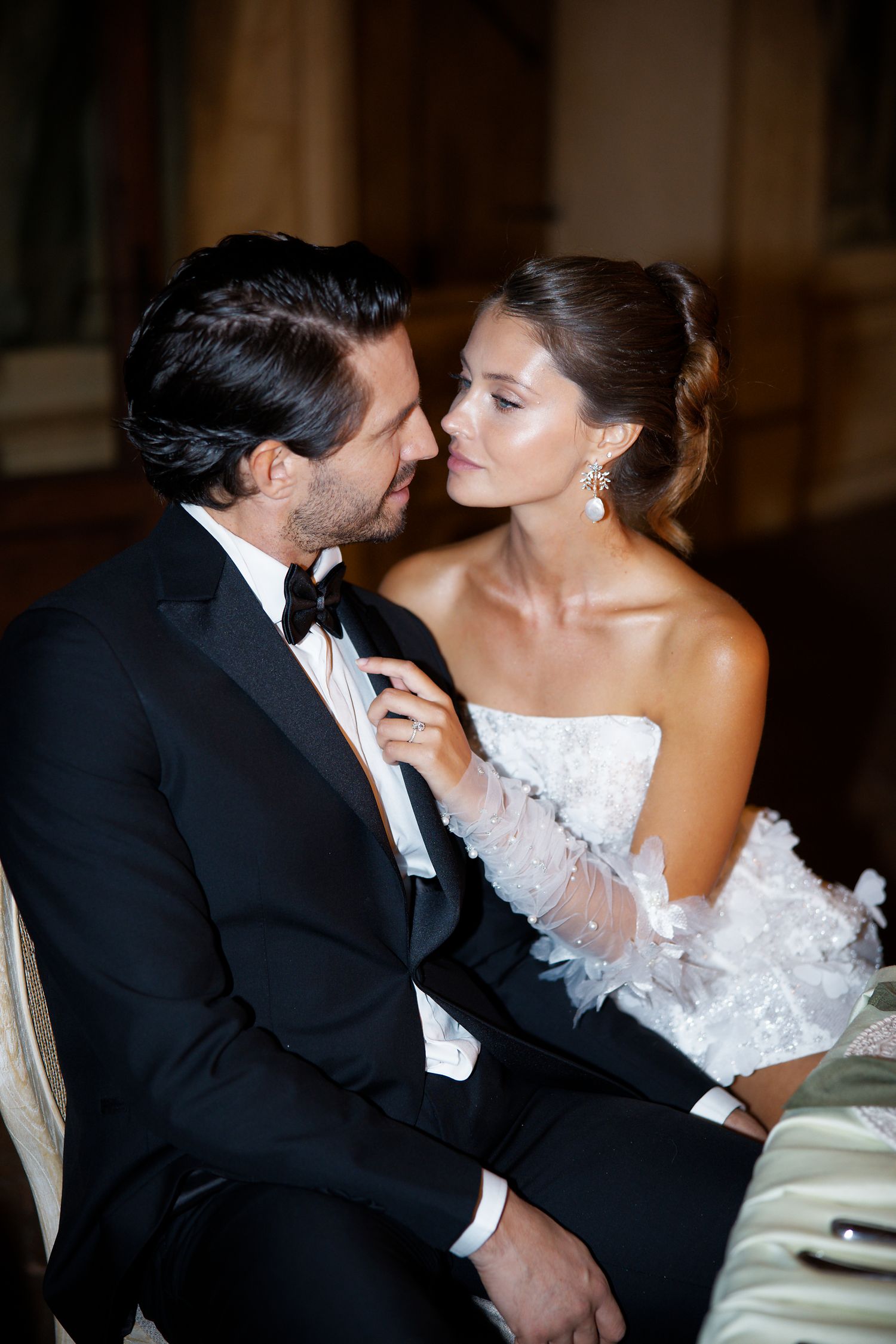 A romantic moment between newlyweds in formal attire at an elegant indoor venue.