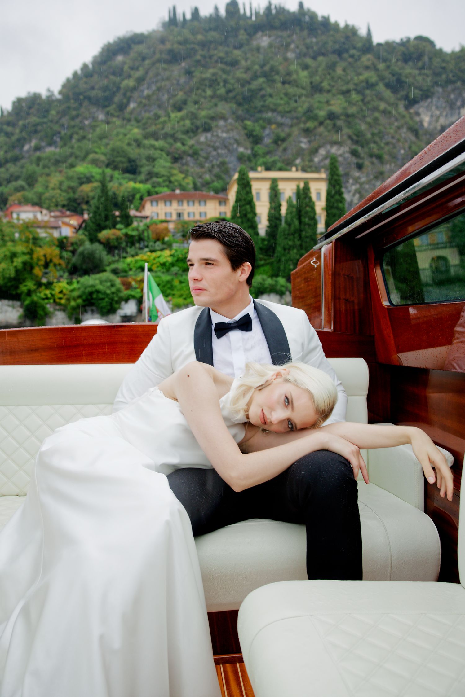 A couple relaxes on a luxury boat with scenic mountain views in the background.