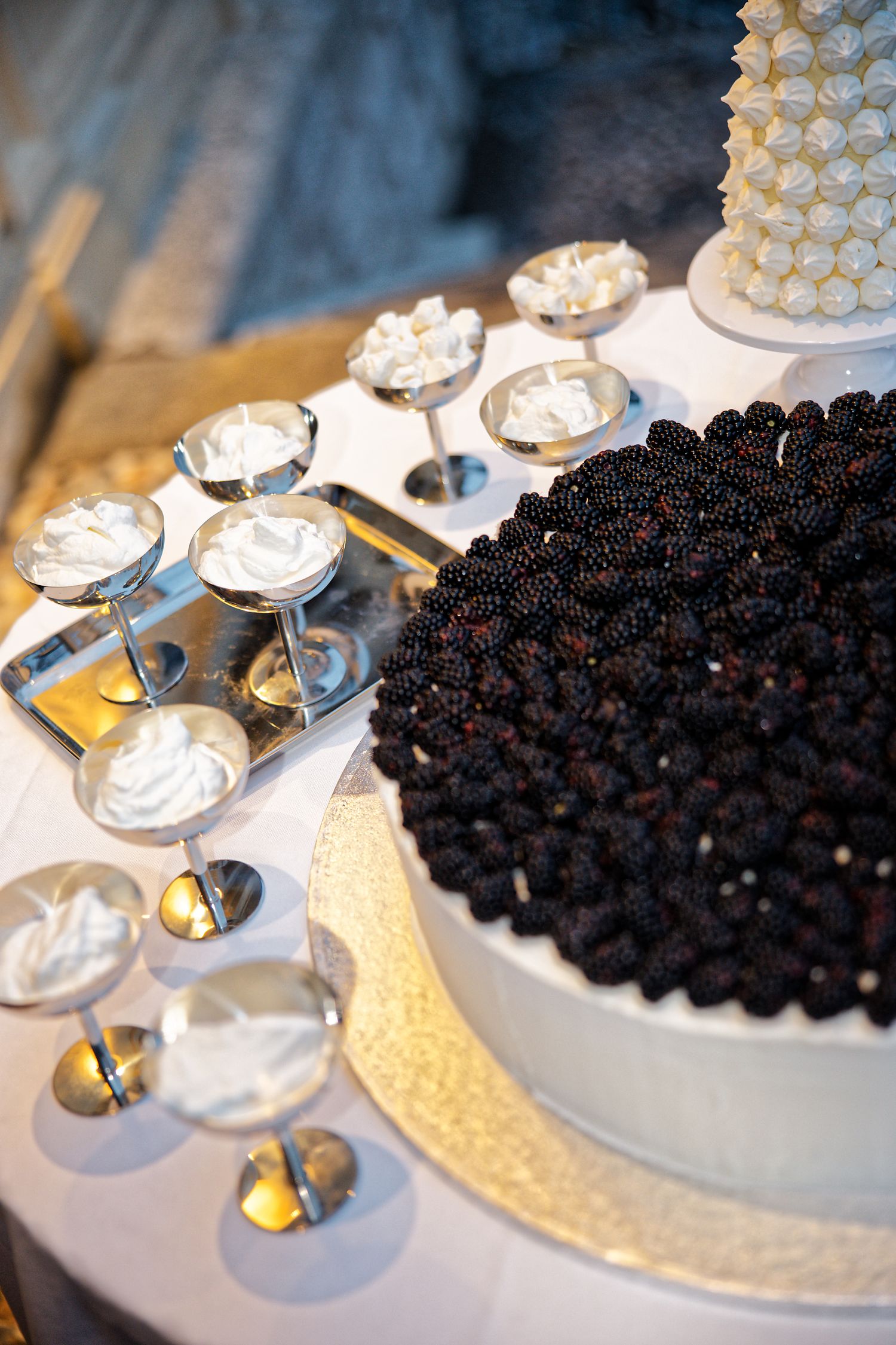 Elegant dessert display featuring white meringue towers and a cake covered in dark berries.