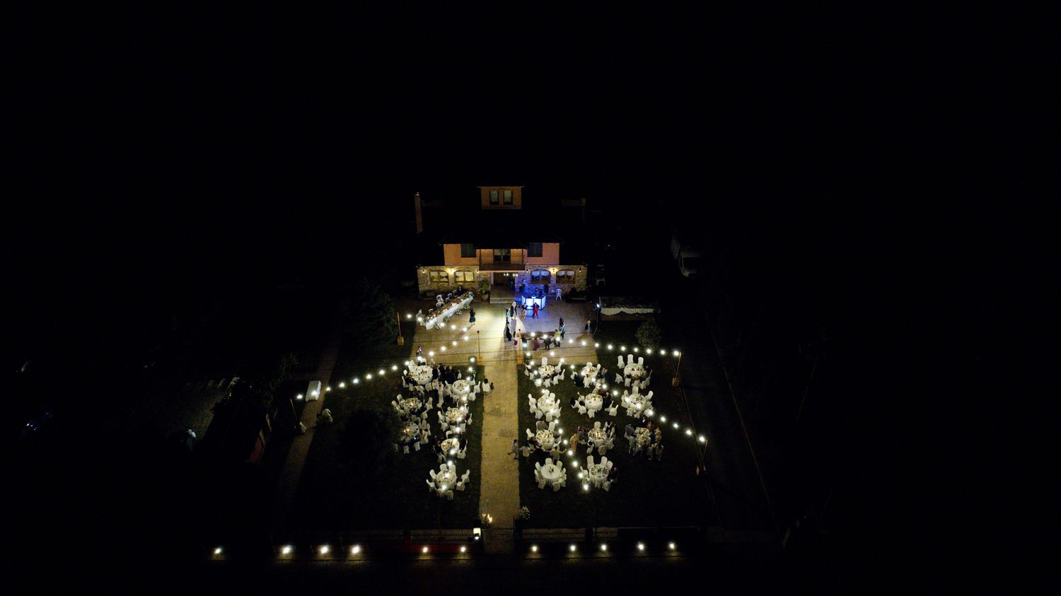 String lights illuminate a church cross against a dark night sky.
