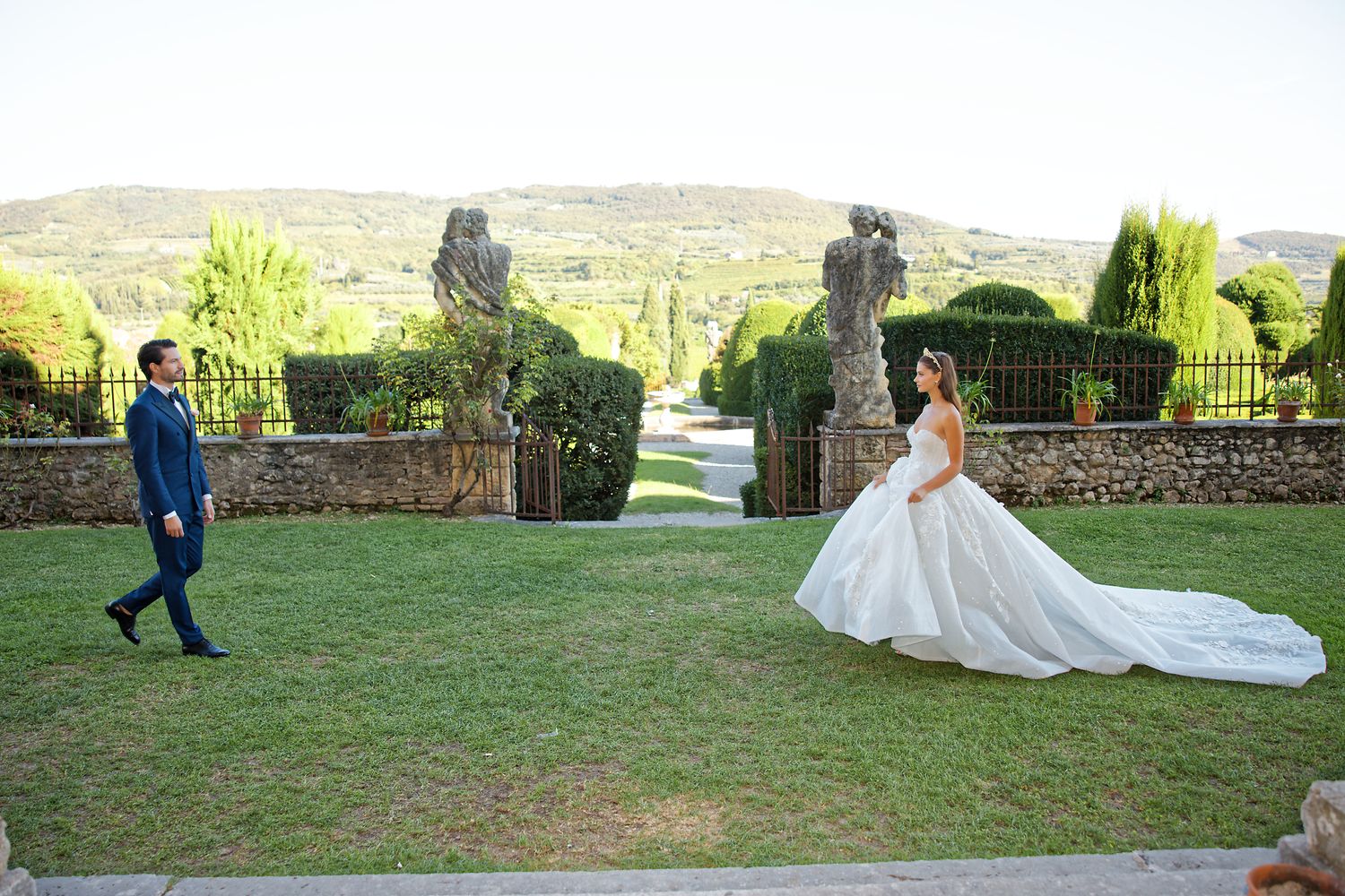 A beautiful wedding photo taken on a scenic garden lawn with a castle-like setting in the background.
