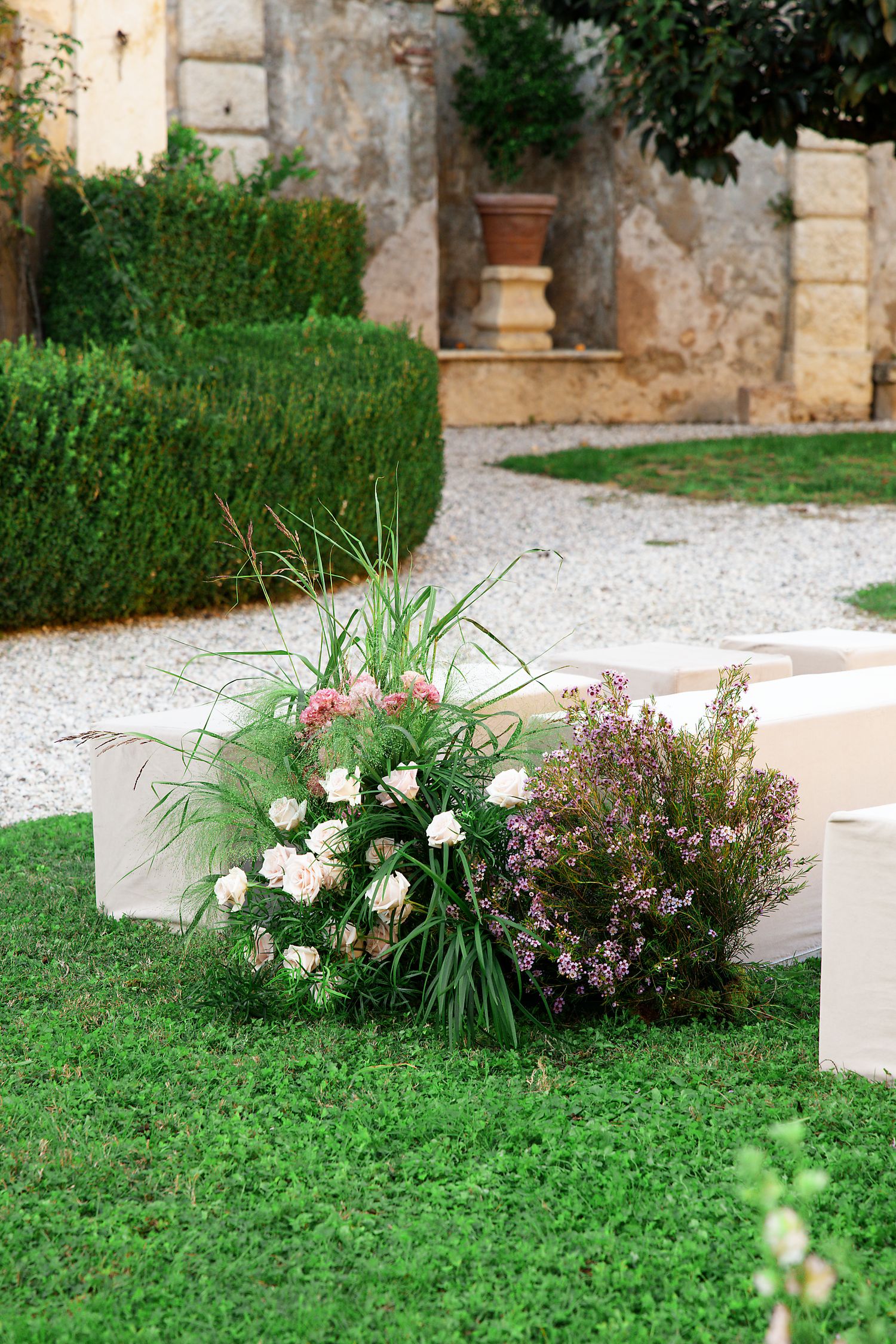 Garden landscaping features white roses and purple flowers against stone wall.