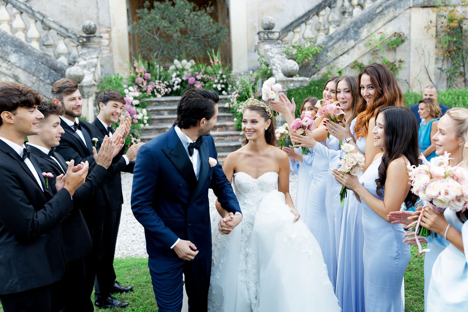 Wedding celebration with bridal party in light blue dresses and black suits on stone steps.