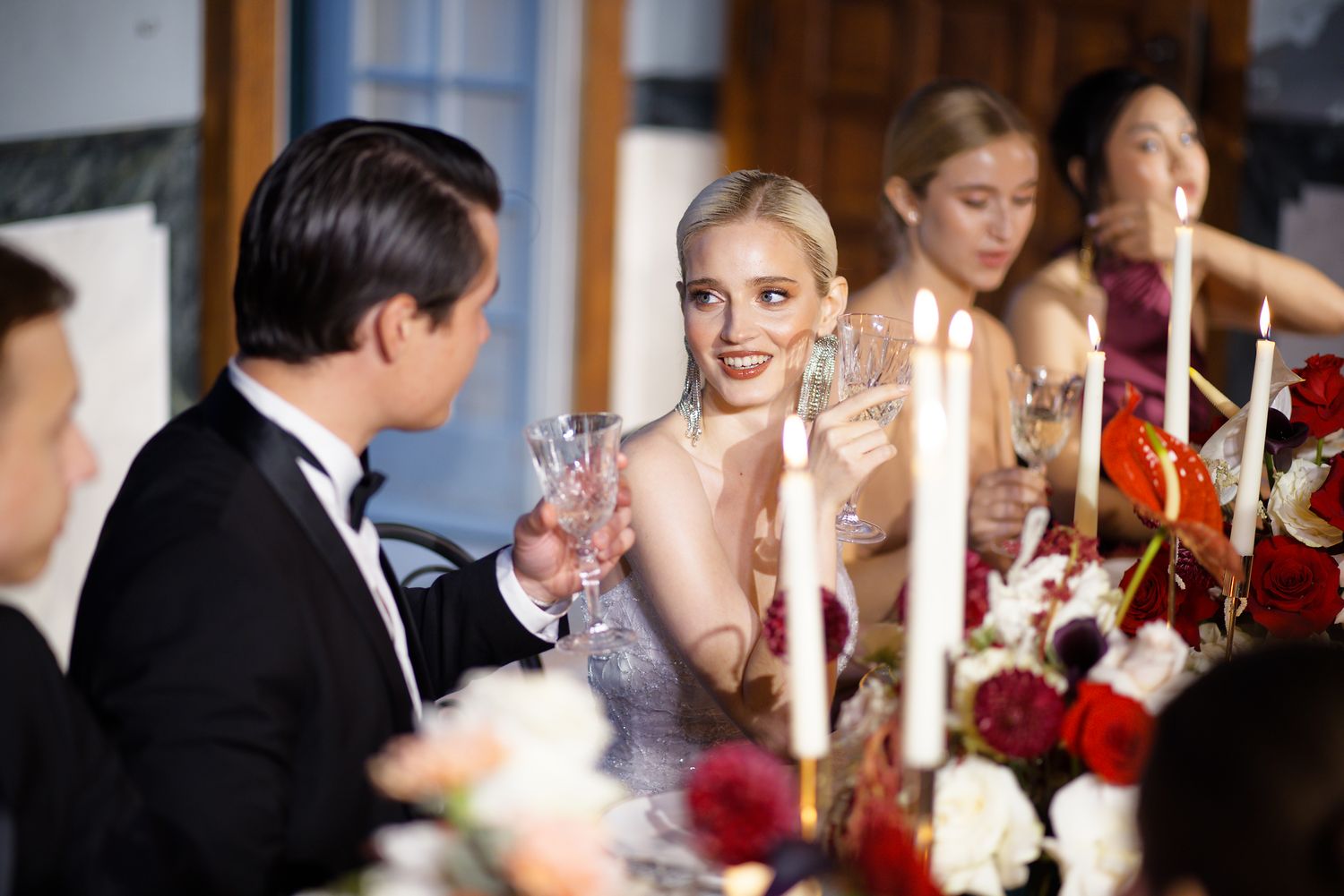 An elegant wedding reception dinner scene with floral centerpieces and candlelight.