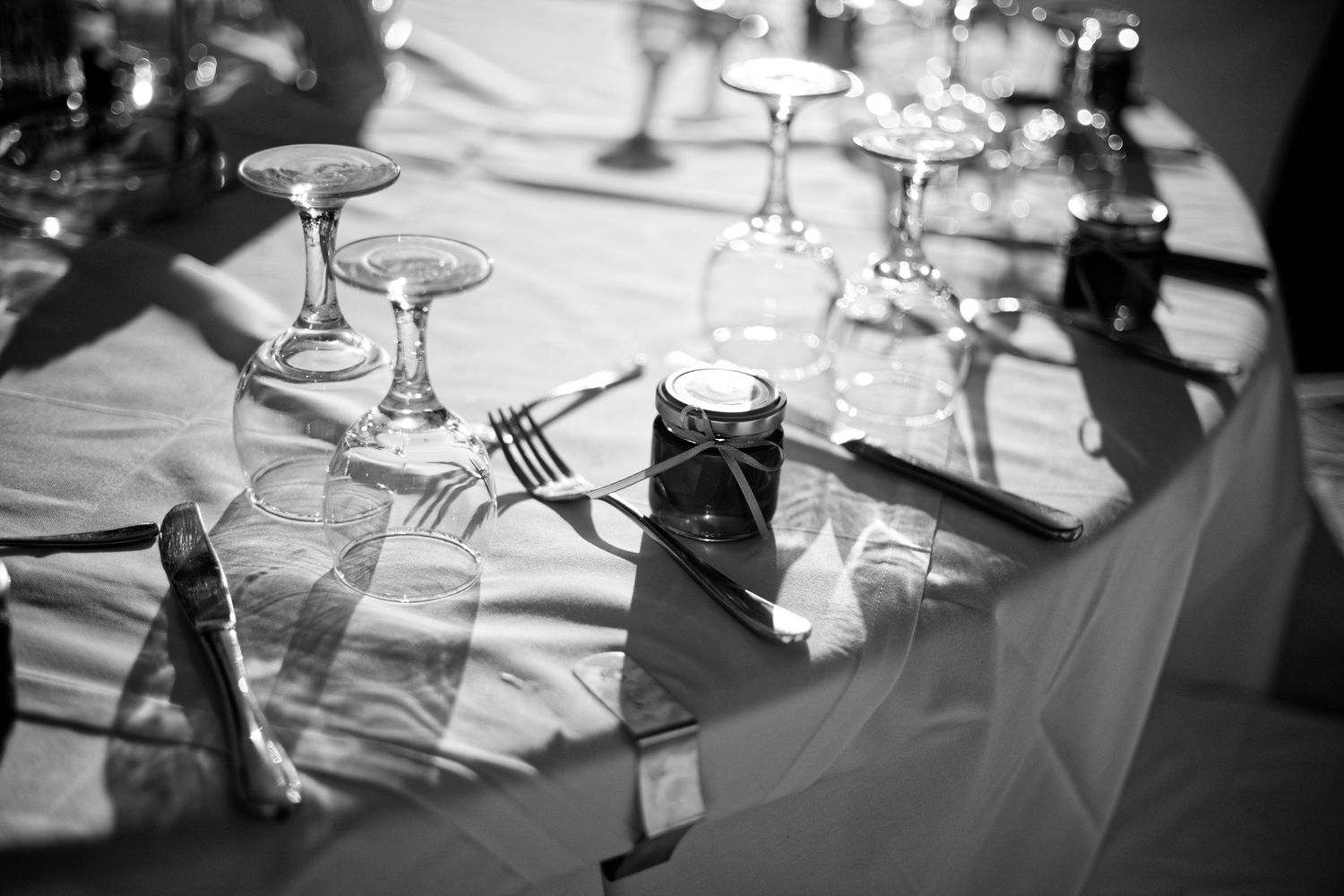 Elegant wedding table setting with wine glasses and silverware in dramatic lighting.