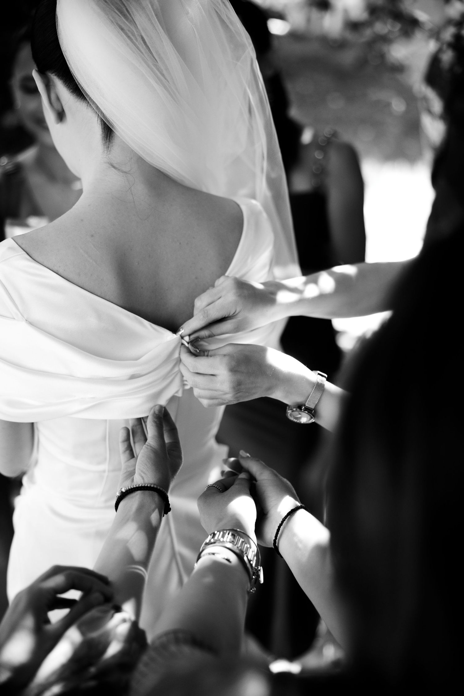 Black and white photo showing the back of a wedding dress being fastened.