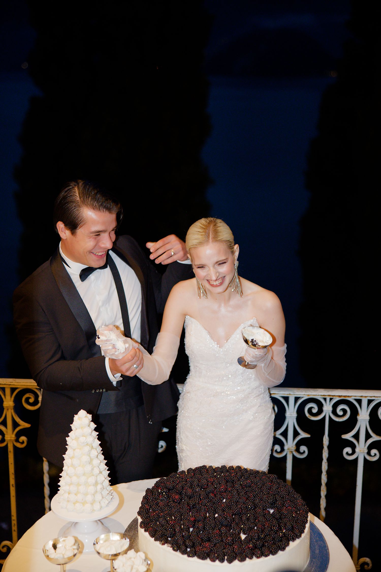 A bride and groom share a joyful moment while cutting their wedding cake at an elegant reception.