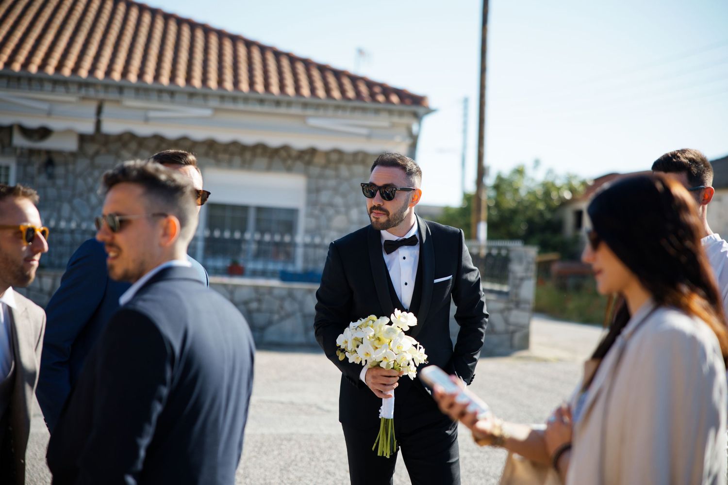 Wedding guests mingling outdoors near a Mediterranean style building.