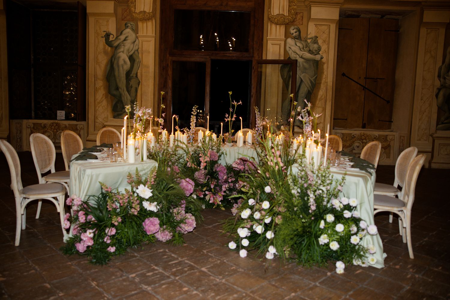 Romantic wedding reception table with lavish floral arrangements and candlelight settings.
