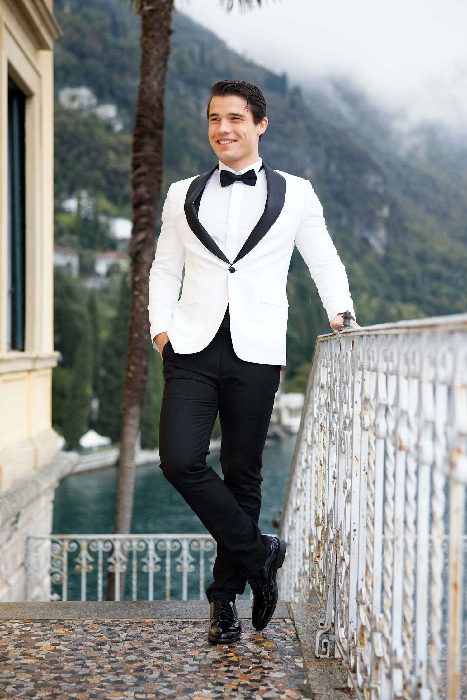 Elegant white tuxedo jacket styled against scenic coastal mountain background.