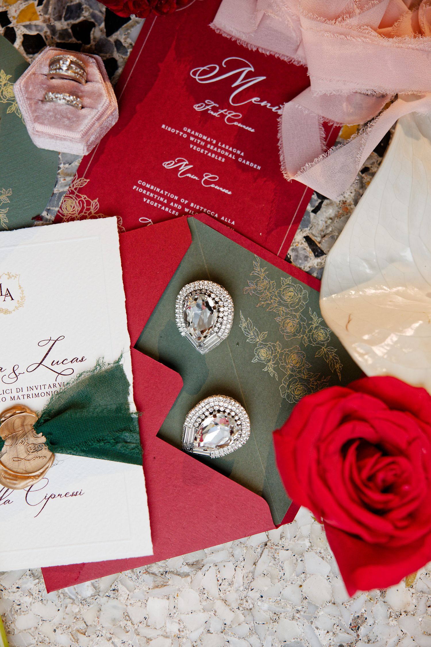 Wedding invitation suite in red and green with diamond jewelry and rose accents.