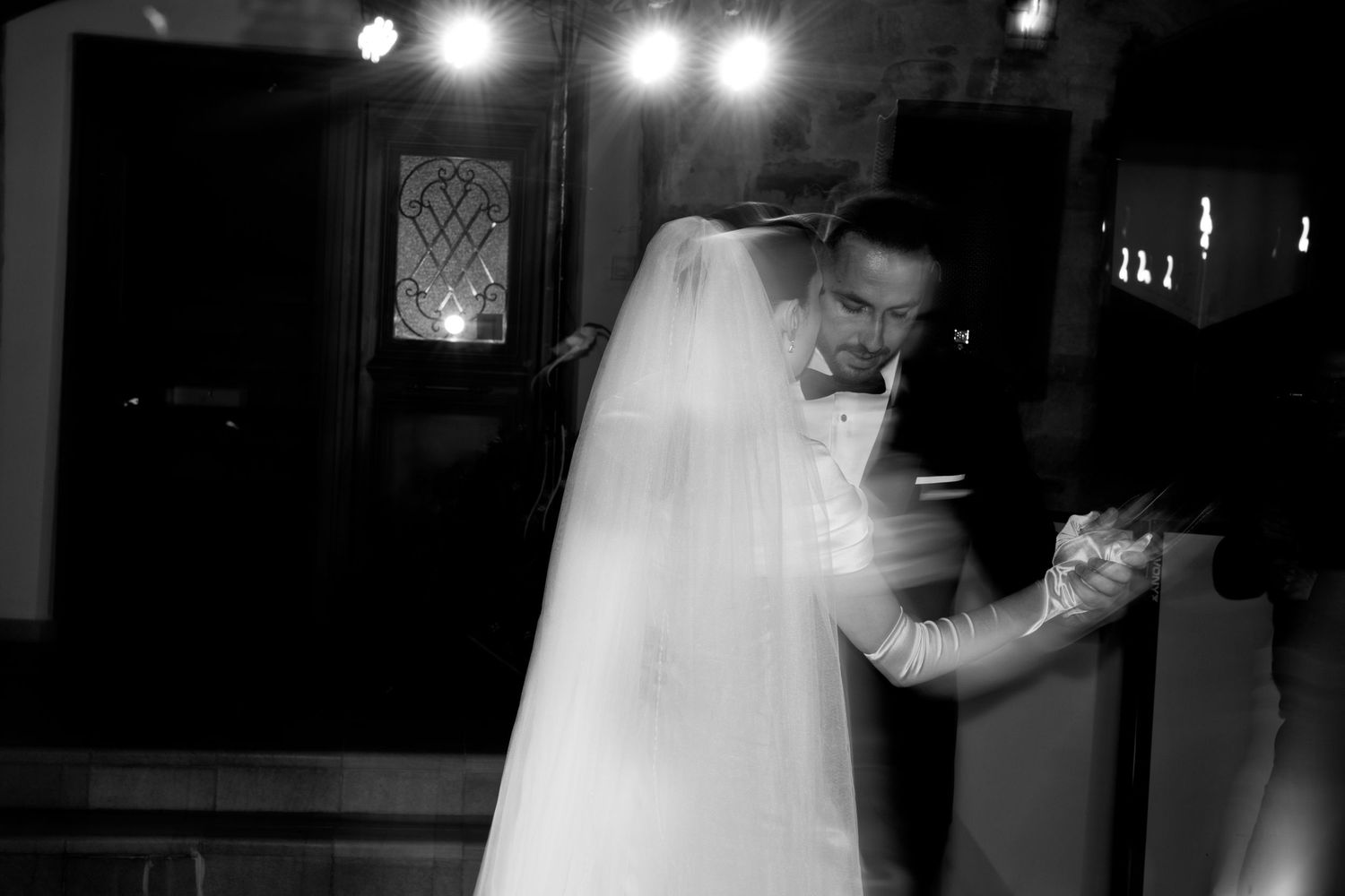 Black and white photos of bride and wedding party dancing at reception with dramatic lighting.