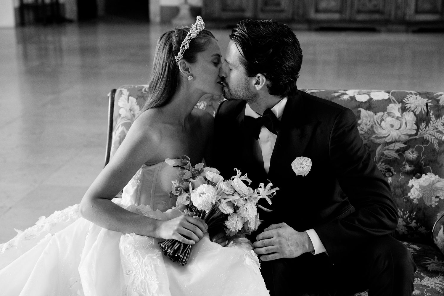 A romantic black and white wedding photo shows a couple sharing an intimate moment while holding a bouquet.
