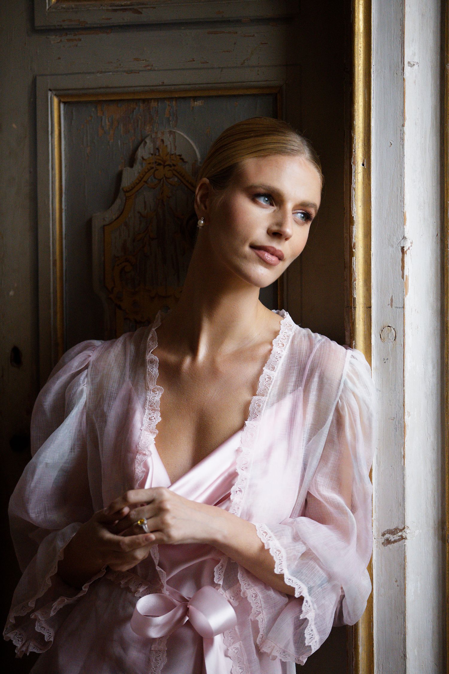 A moody bridal boudoir portrait by a window with soft natural lighting.