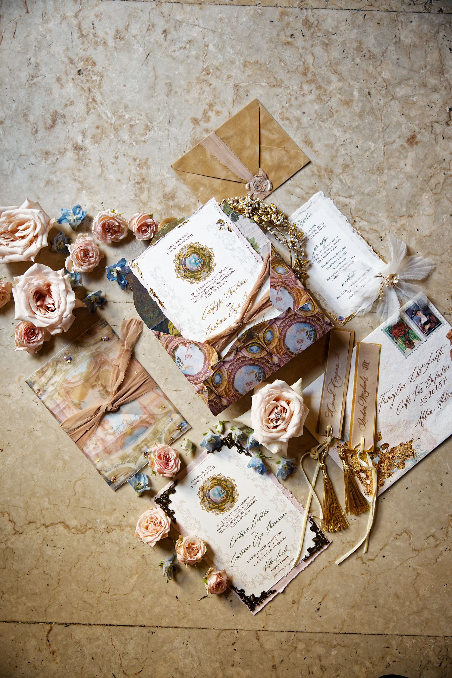 Elegant wedding invitations with peach roses and gold accents arranged on a textured surface.
