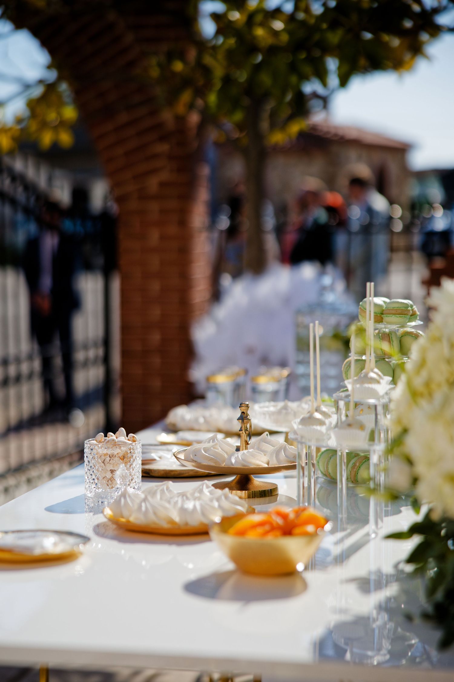 Elegantly set outdoor wedding reception table with glassware, plates and floral arrangements.