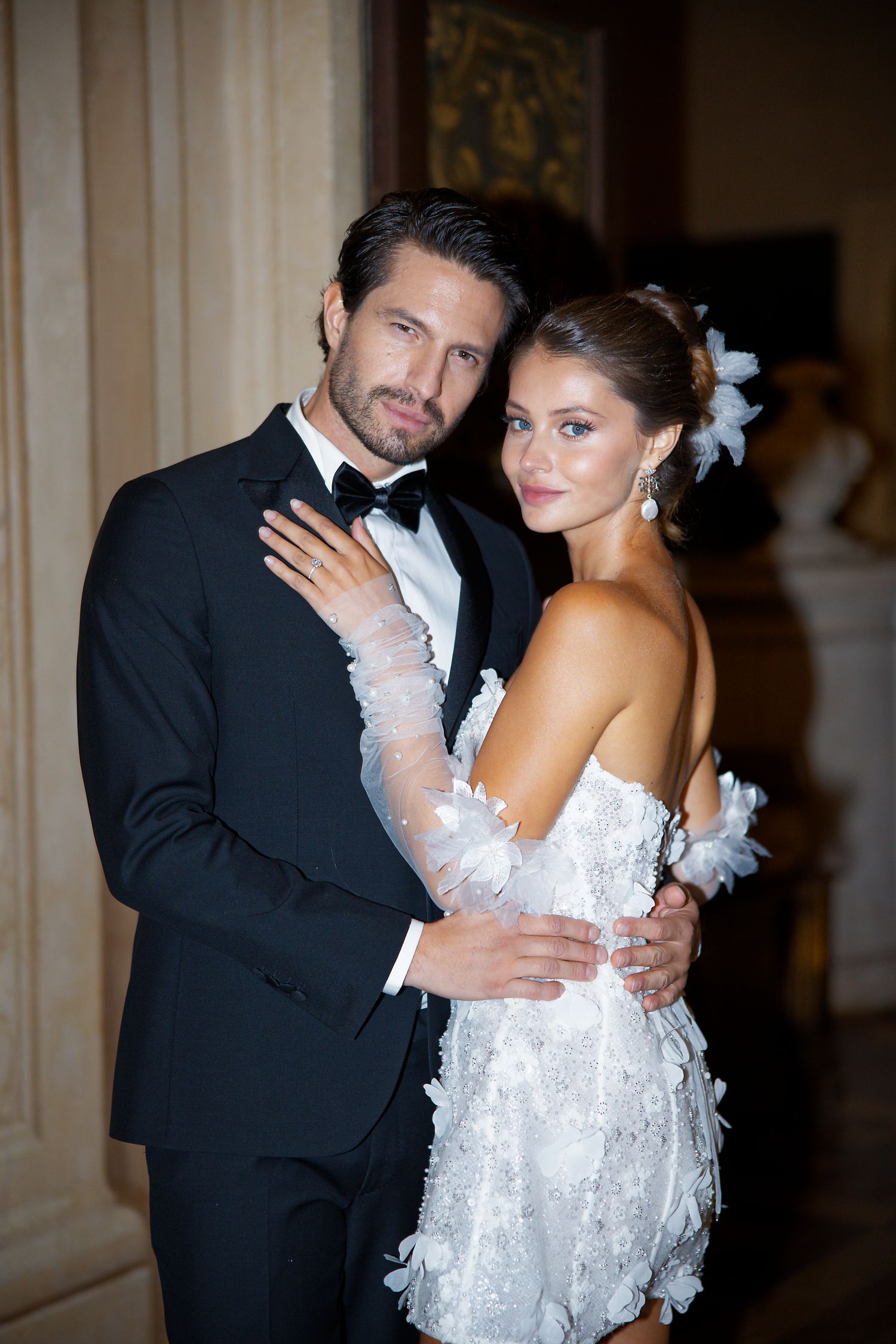 A glamorous couple in formal evening wear embrace during their wedding celebration.