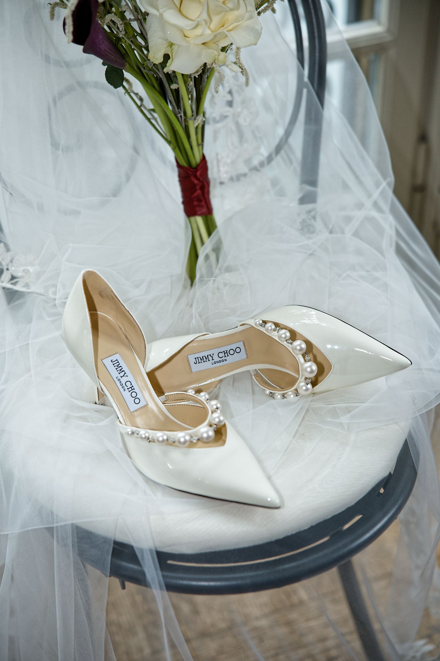 Elegant white Jimmy Choo bridal shoes with pearl details on tulle veil.