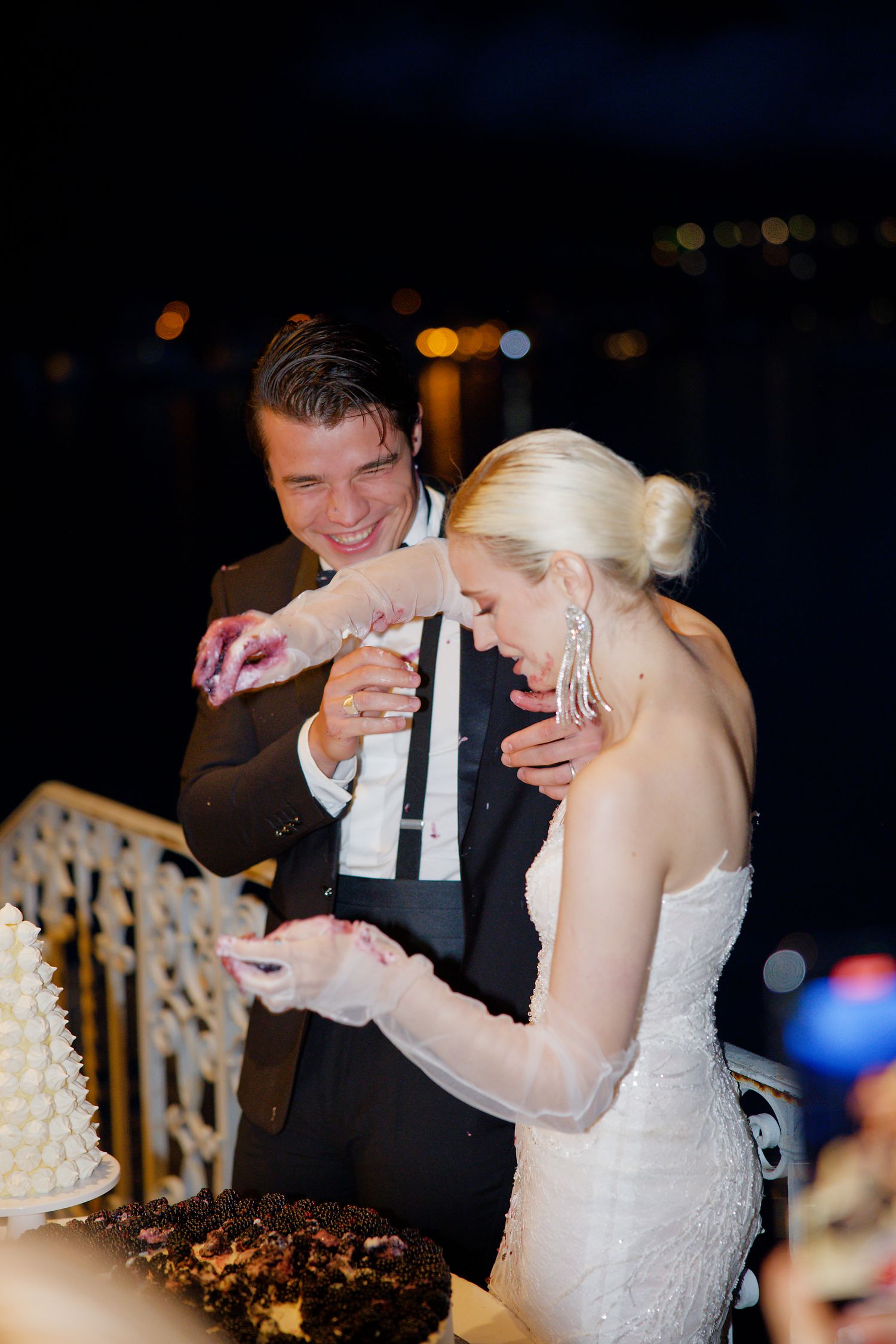 Wedding couple sharing cake cutting moment at evening reception.