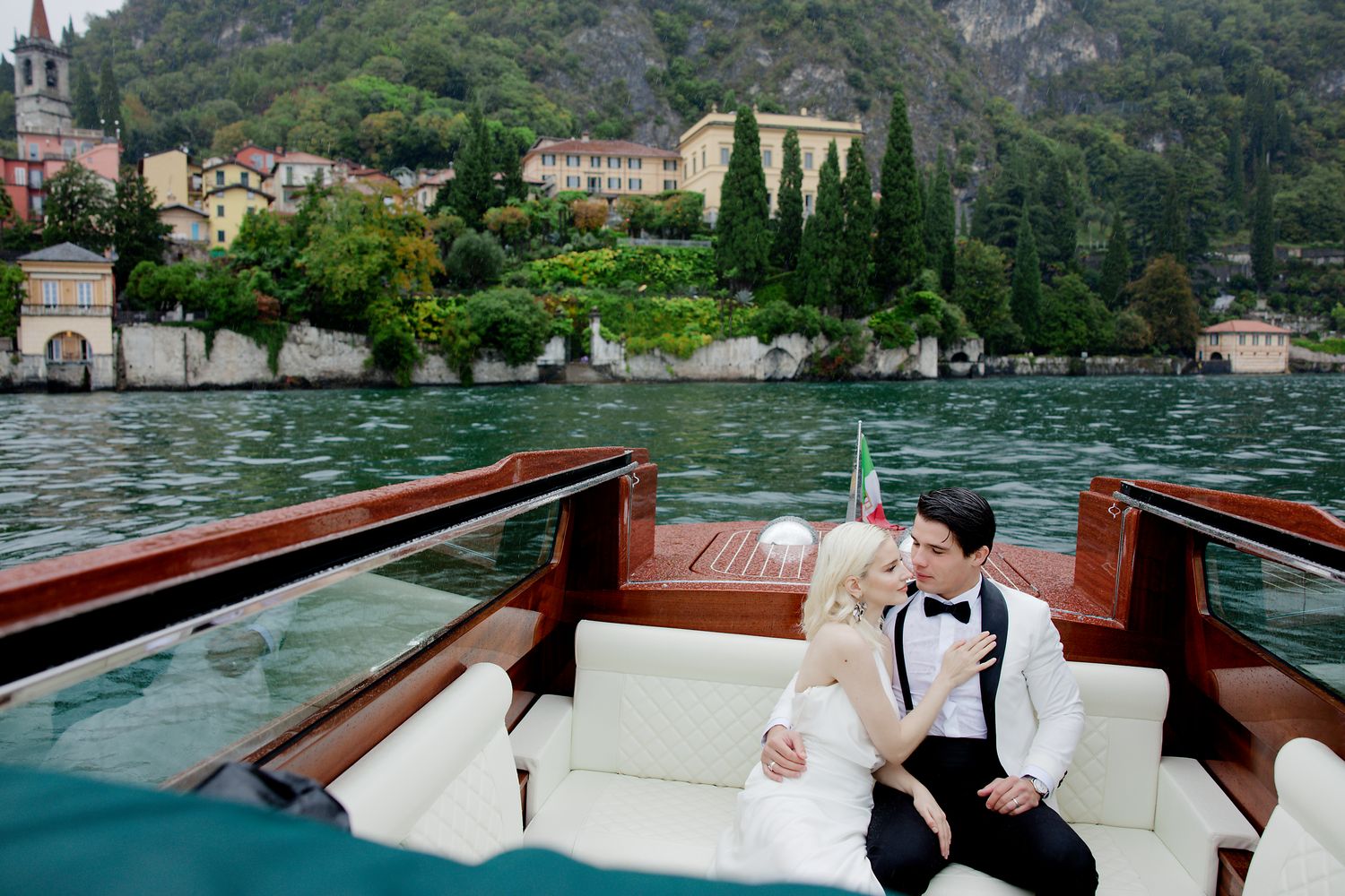 Romantic boat ride on Lake Como with mountainous Italian village backdrop and historic architecture.