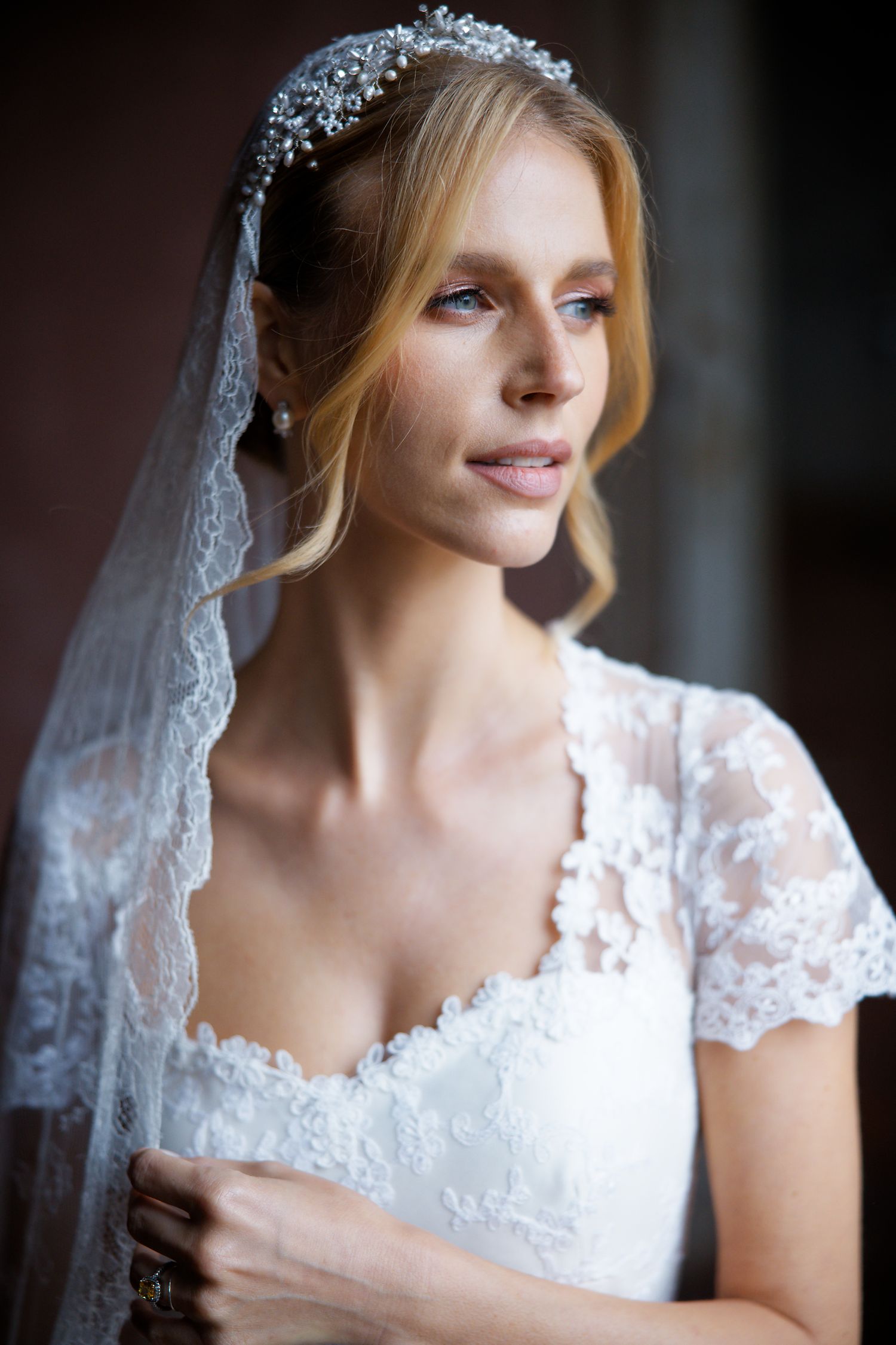 Elegant bride wearing lace wedding dress with crystal headpiece and veil.