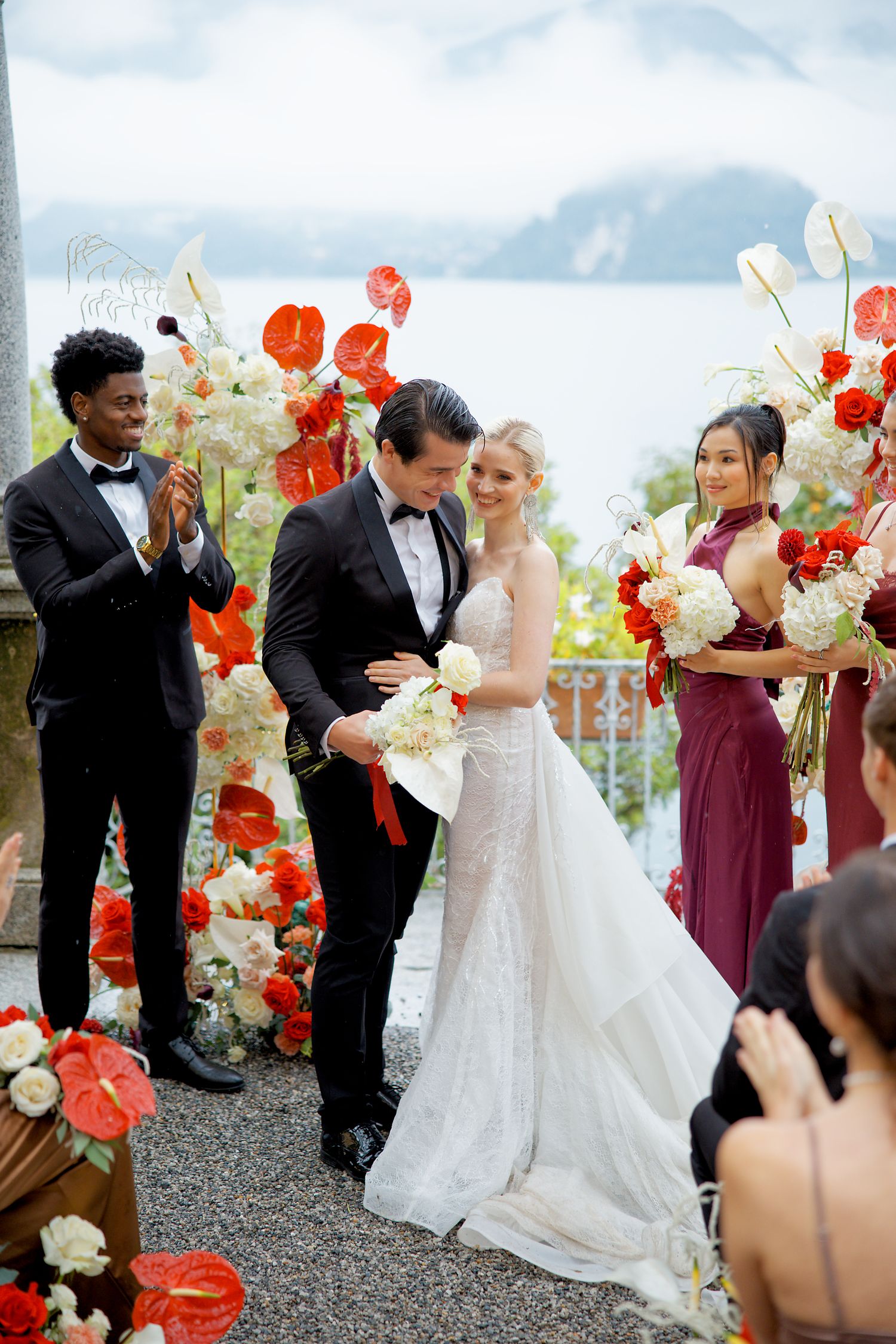 A wedding ceremony on a scenic mountain backdrop with beautiful red and white floral arrangements.