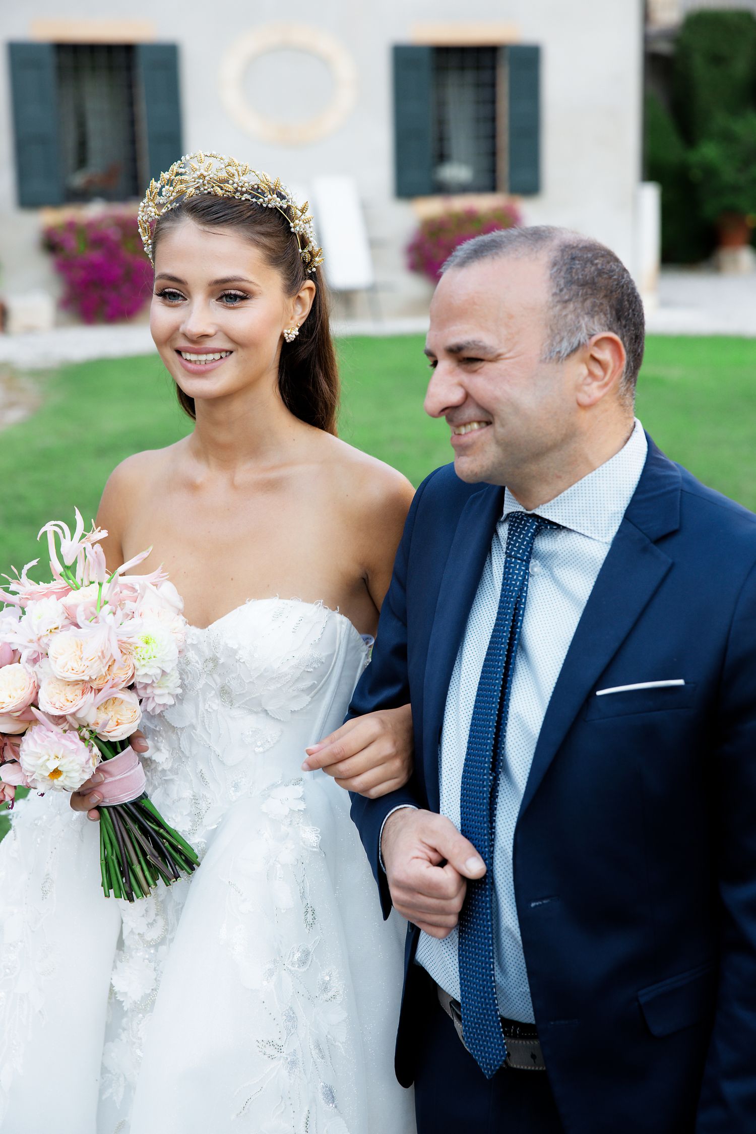 A wedding couple in formal attire sharing a joyful moment with pink bouquet.