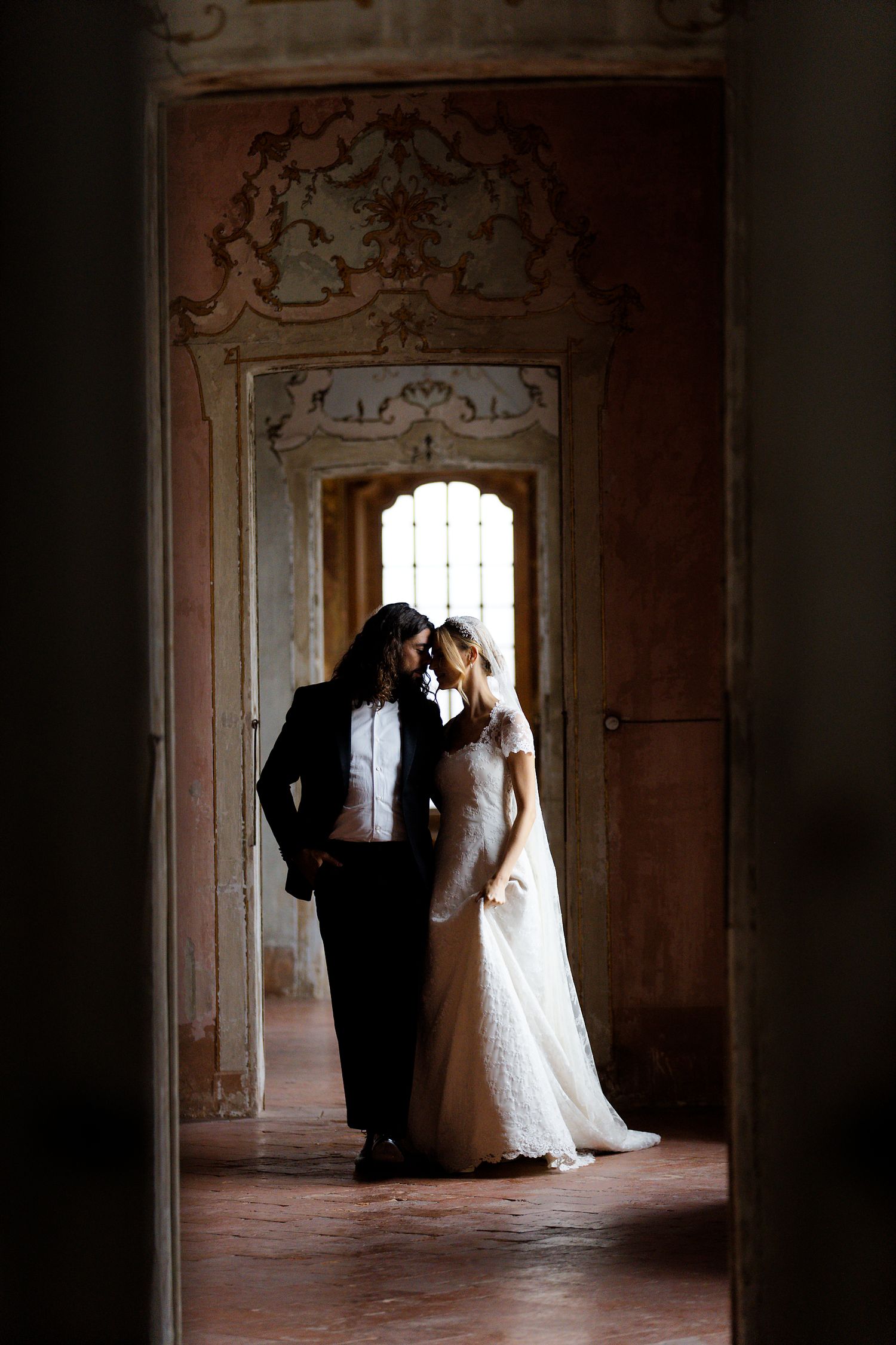 A silhouetted couple shares an intimate moment in an ornate vintage doorway.