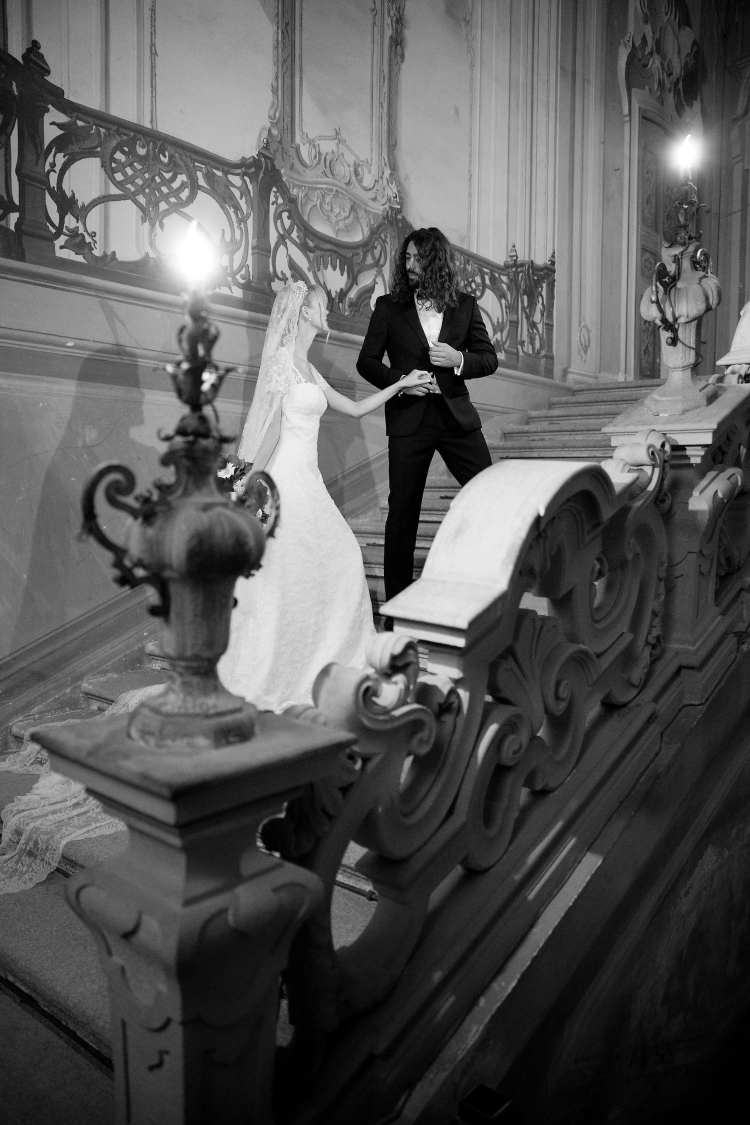 Black and white photo of a couple on an ornate staircase during what appears to be a wedding ceremony.