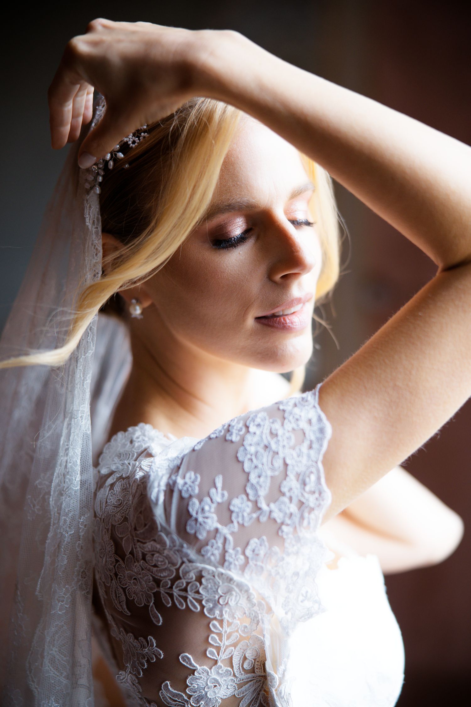 Ethereal bridal portrait with delicate lace details and flowing veil in soft natural light.