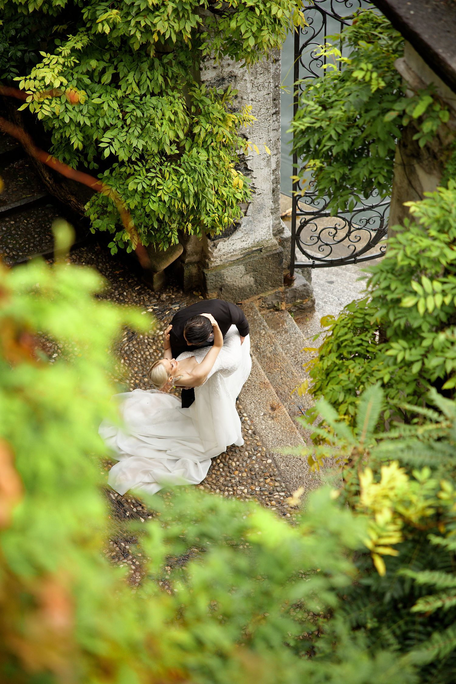 Aerial view of romantic wedding moment in garden with ornate stone steps.