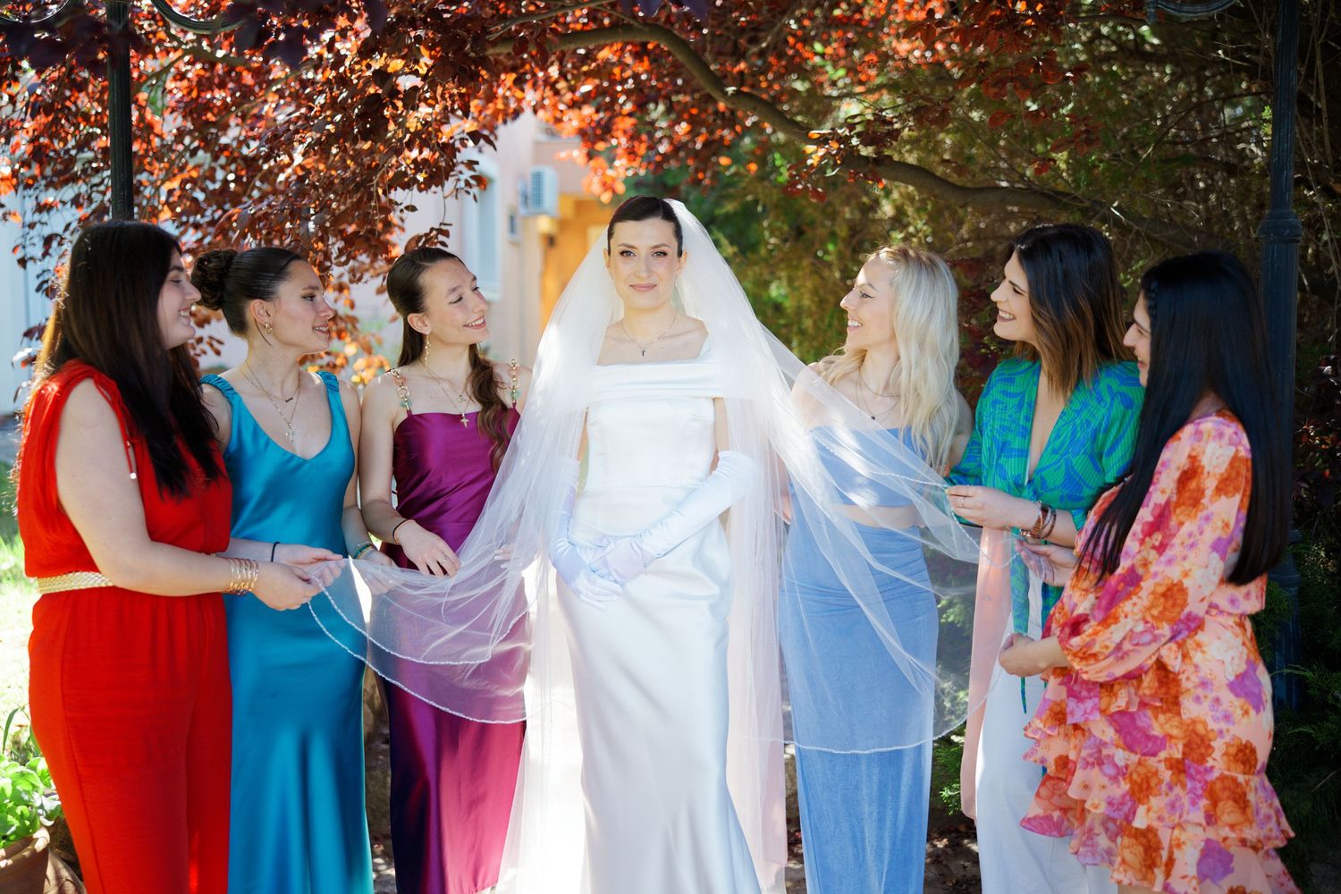 Bridesmaids and bride in pastel blue and floral dresses lined up at outdoor wedding ceremony.