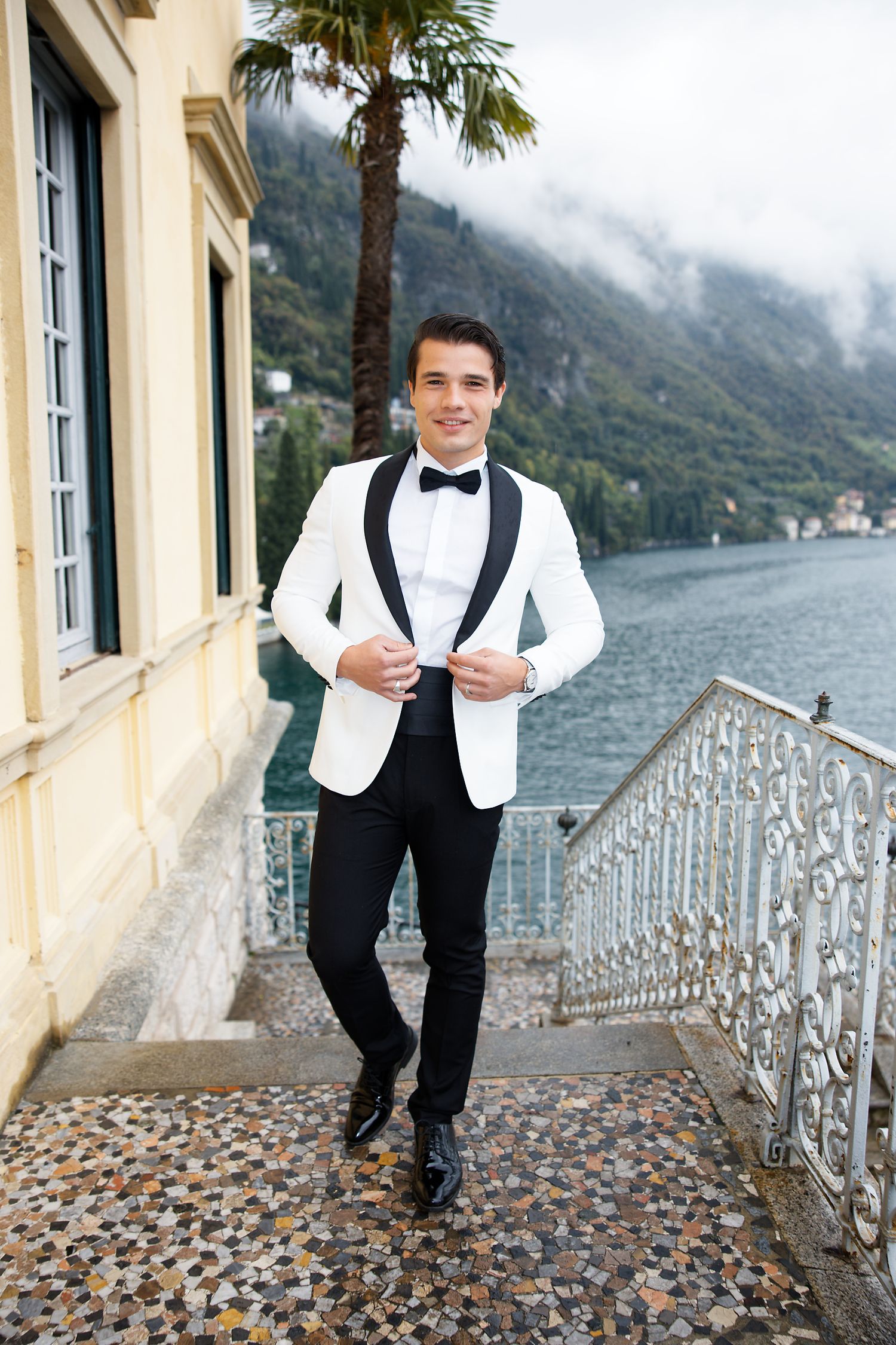 Classic white tuxedo portrait against stunning Lake Como villa backdrop.