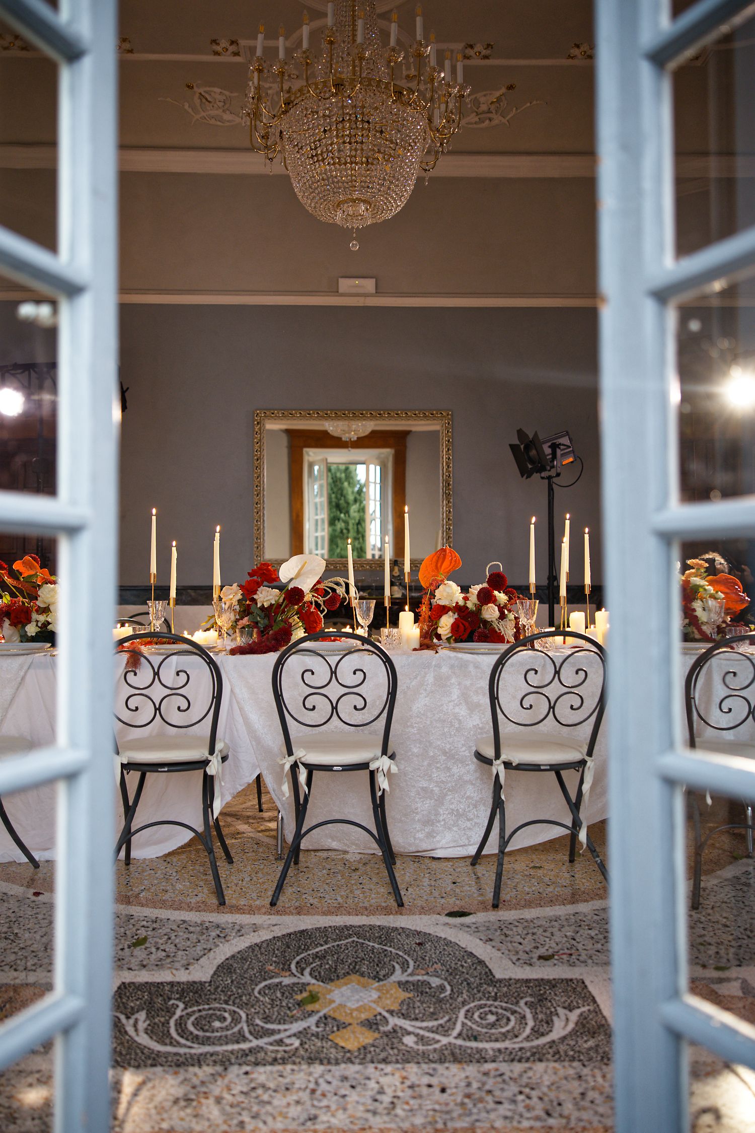 Elegant wedding reception table with crystal chandelier and fall-themed floral centerpieces.