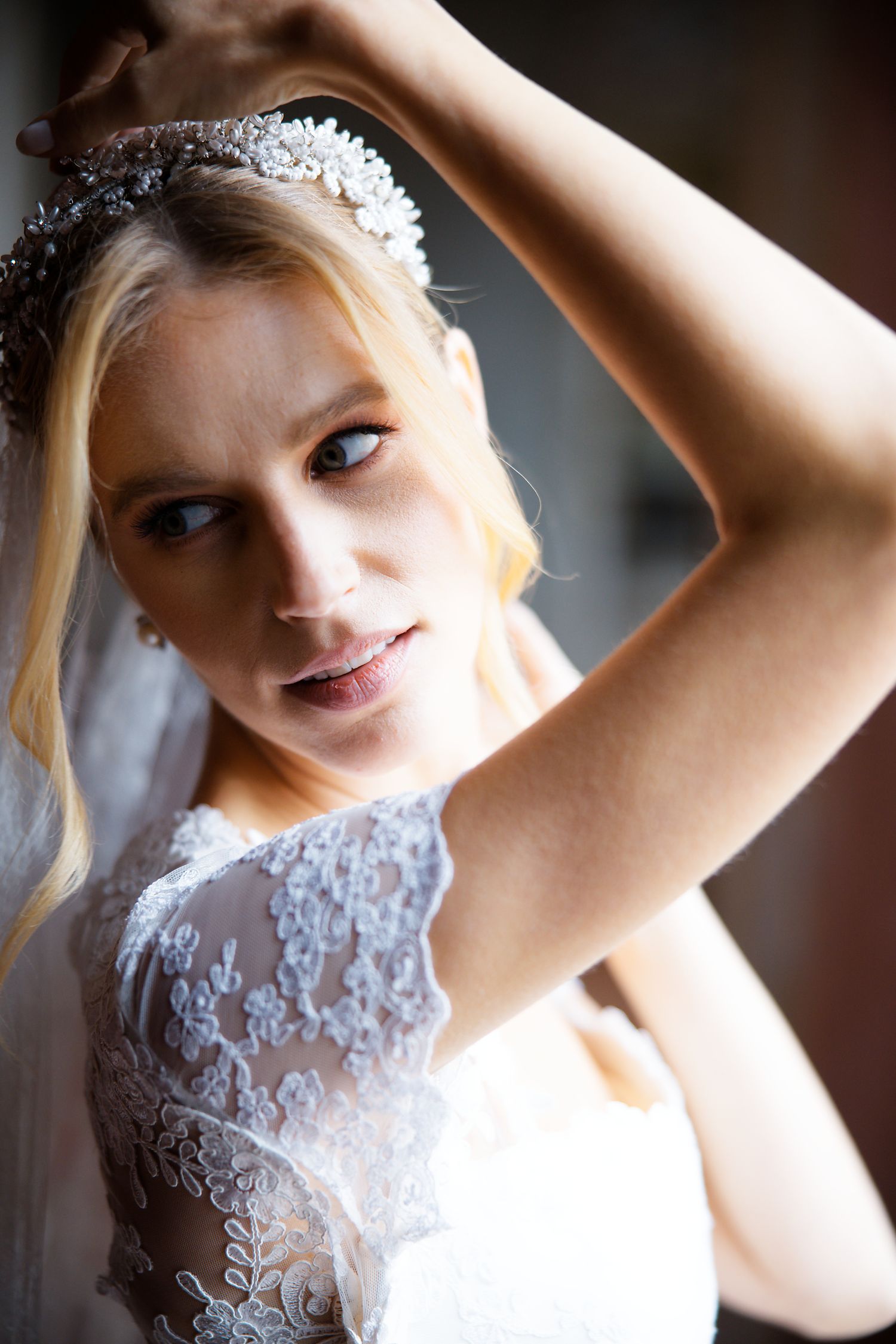 Close-up portrait of bride wearing crystal headpiece and lace wedding gown.