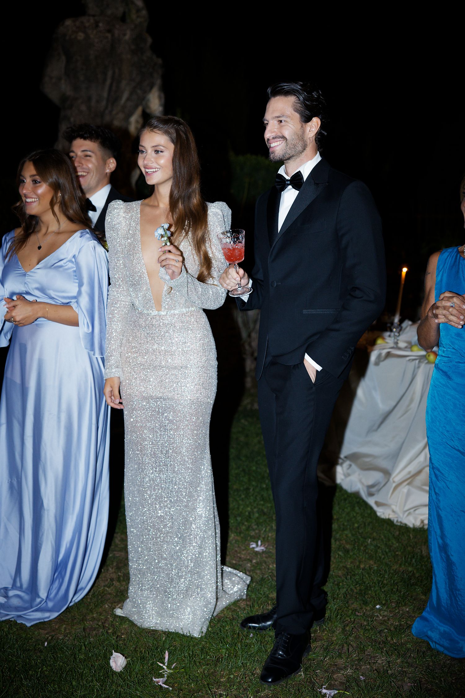 Wedding party guests mingle at an elegant outdoor evening reception.