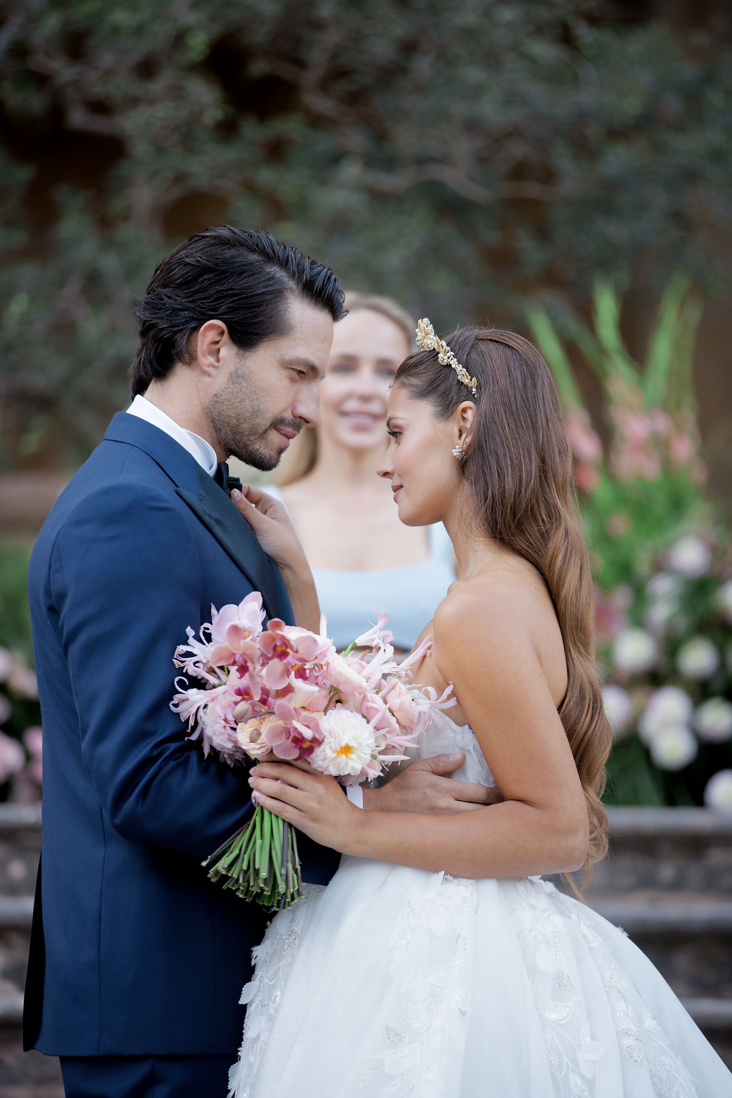 Wedding couple sharing intimate moment with pink bouquet in garden setting.