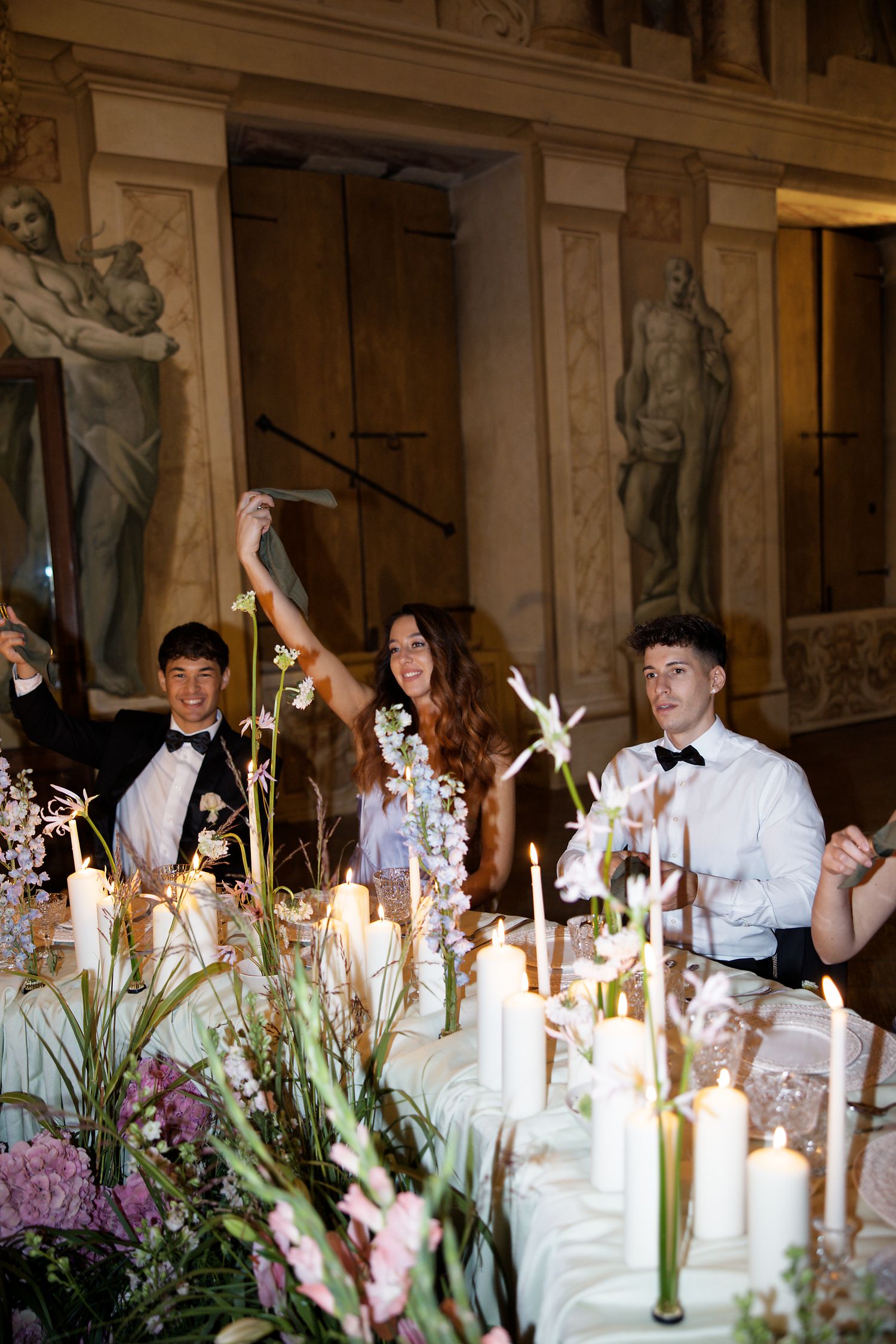Wedding reception dinner table with candles and floral arrangements in grand historic hall.