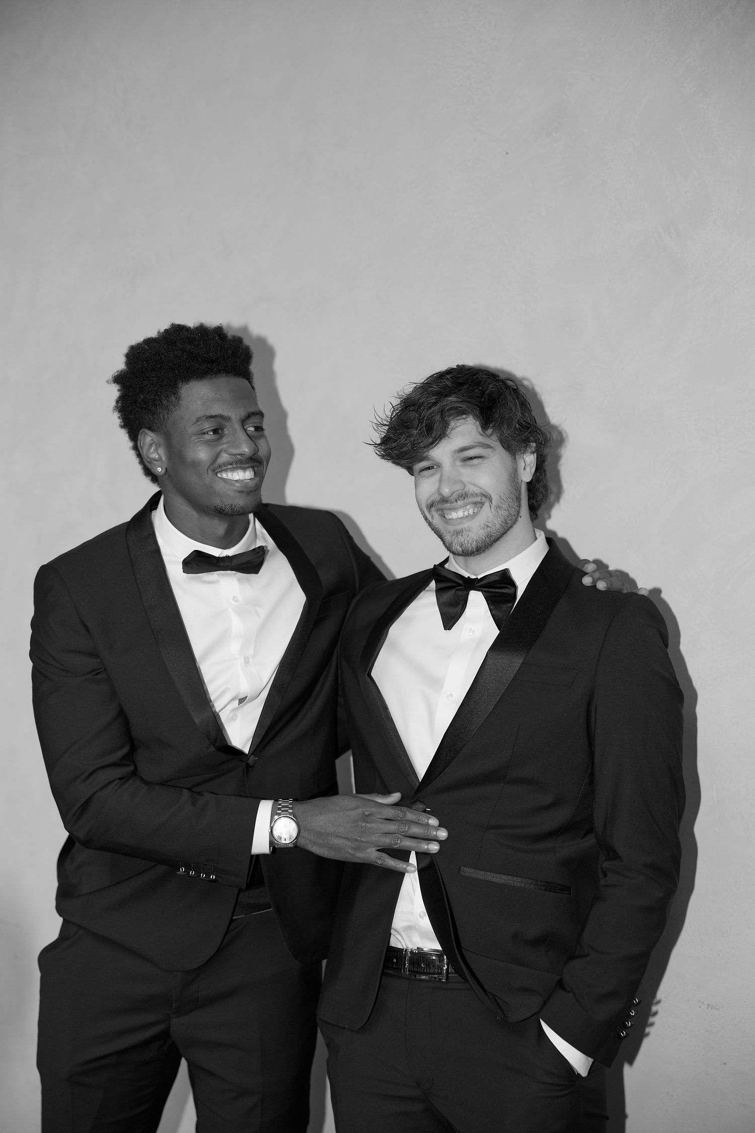 Groomsmen in black tuxedos sharing a candid moment at wedding celebration.