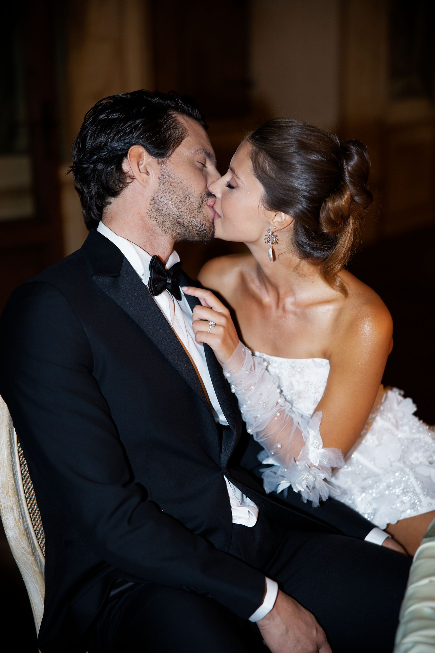 Romantic moment between newlyweds with bride in white lace dress and groom in classic tuxedo.