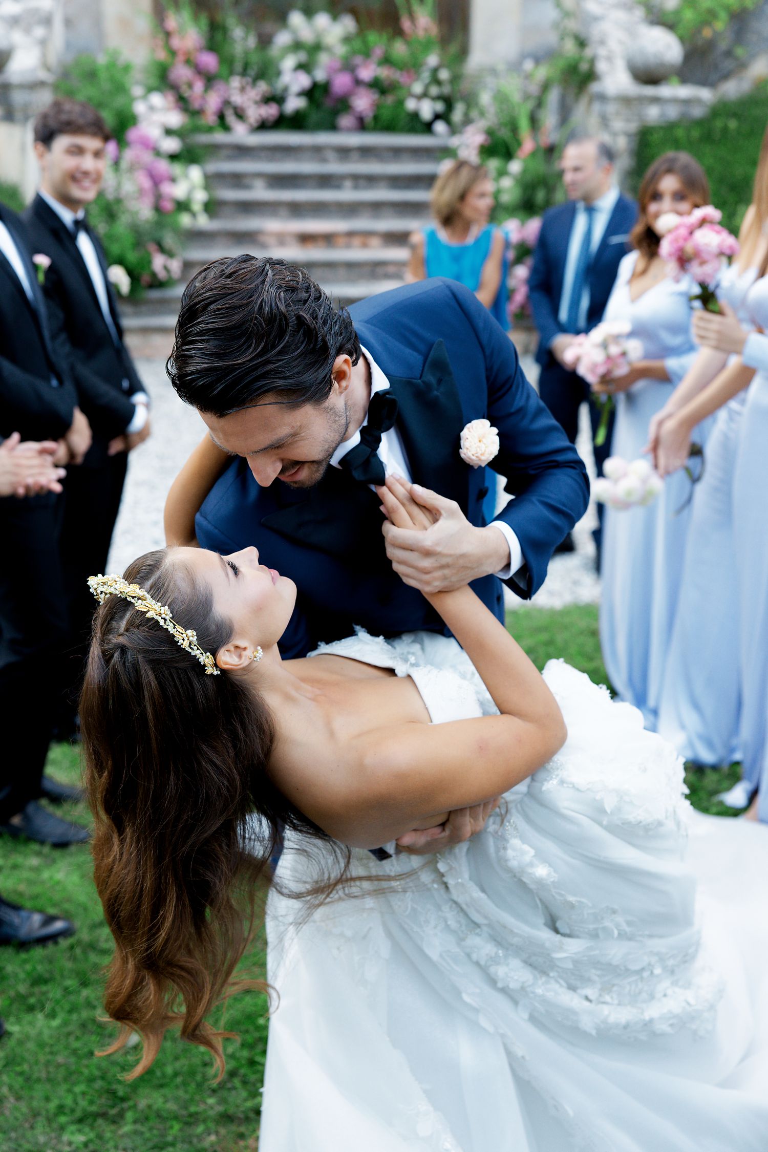 Joyful dip during a wedding dance with bridesmaids in powder blue dresses looking on.