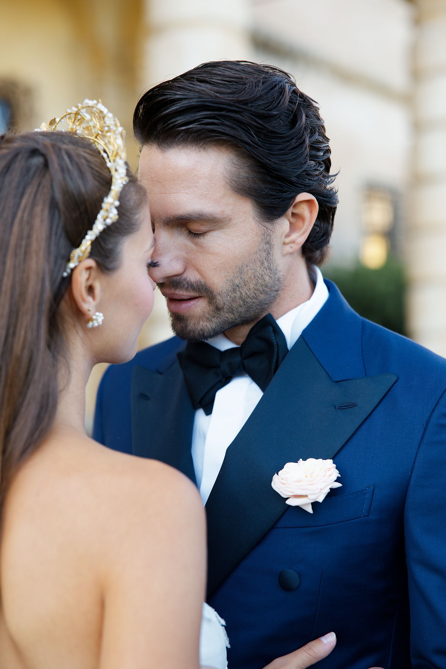 Close up of a wedding couple in formal attire with a white rose boutonniere.