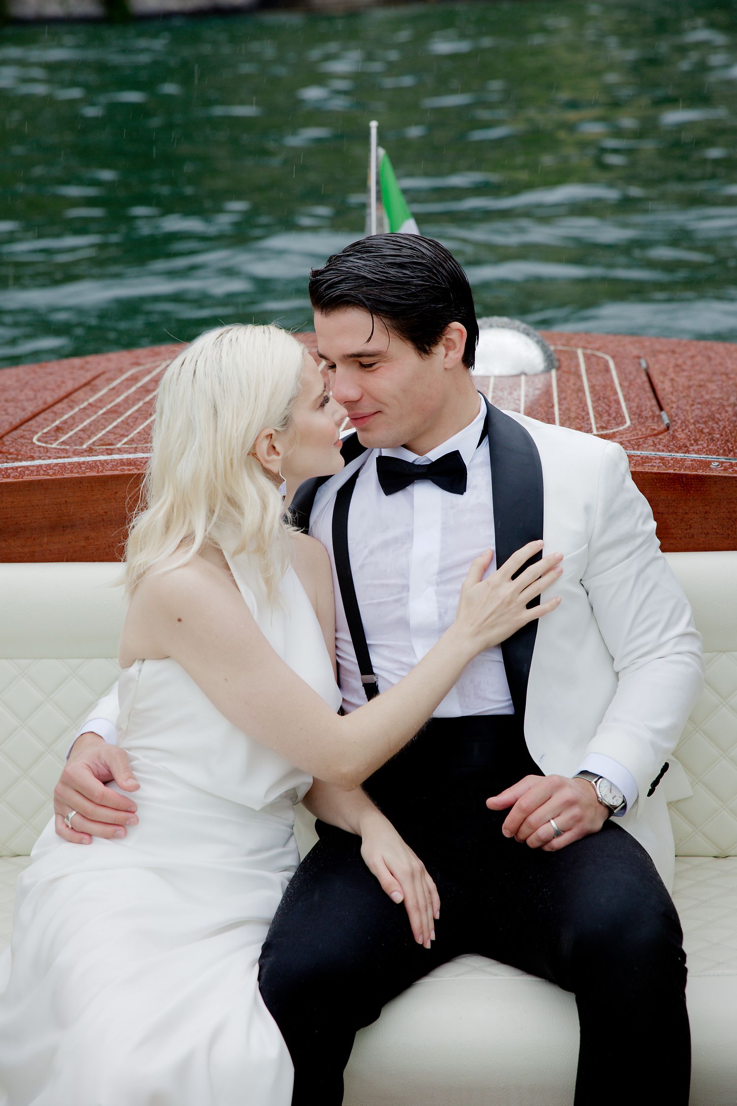 Romantic moment captured on vintage wooden boat with lake backdrop.