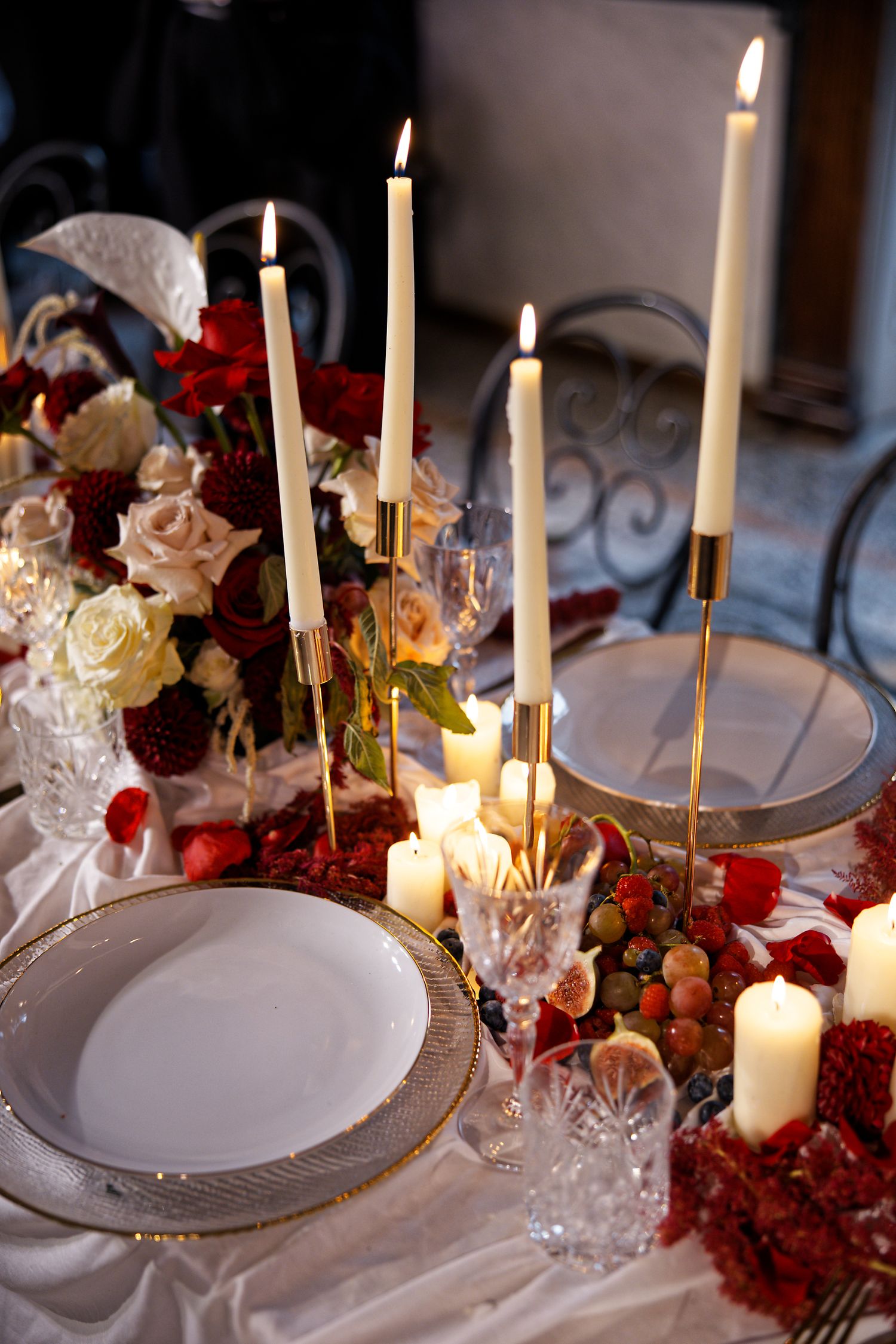 An elegant table setting with tall white candles, crystal glasses and romantic floral arrangements.