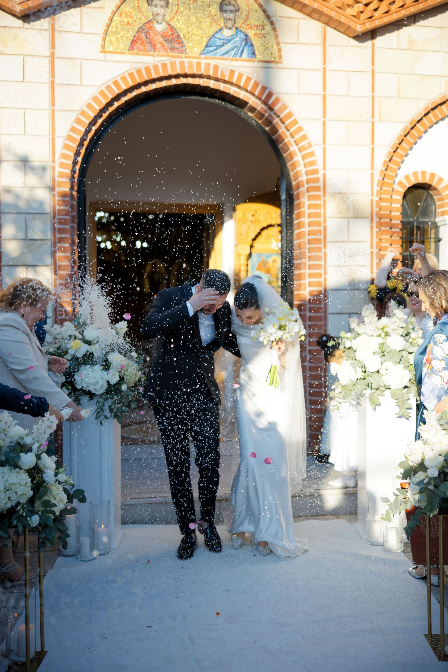 A wedding couple exits a church while guests shower them with rice in a series of celebratory moments.