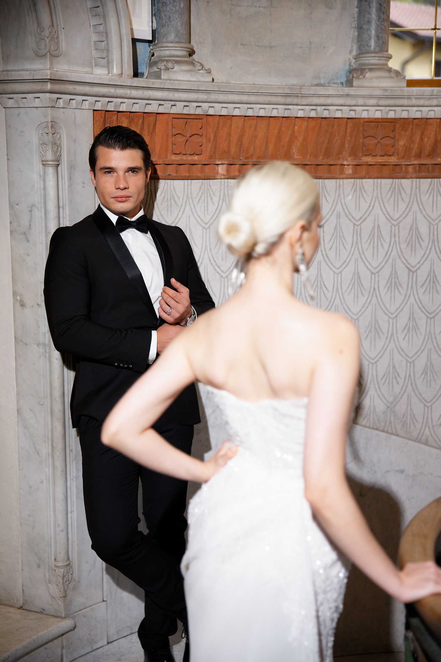 Elegant indoor scene with ornate architectural details and formal attire.